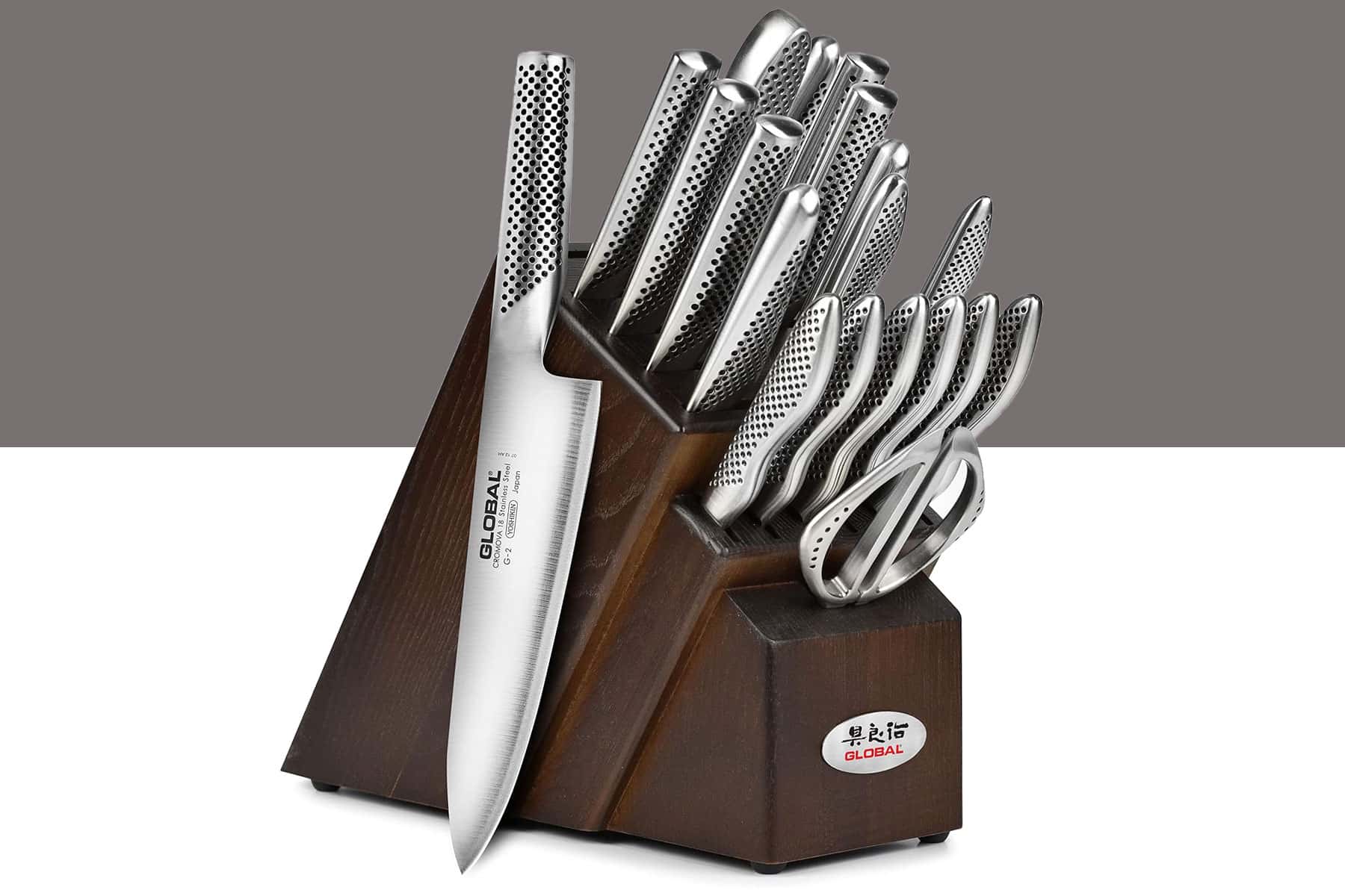 The Global 20-piece knife set shown with the knives inside its storage block except for the chef knife on a split gray and white background..