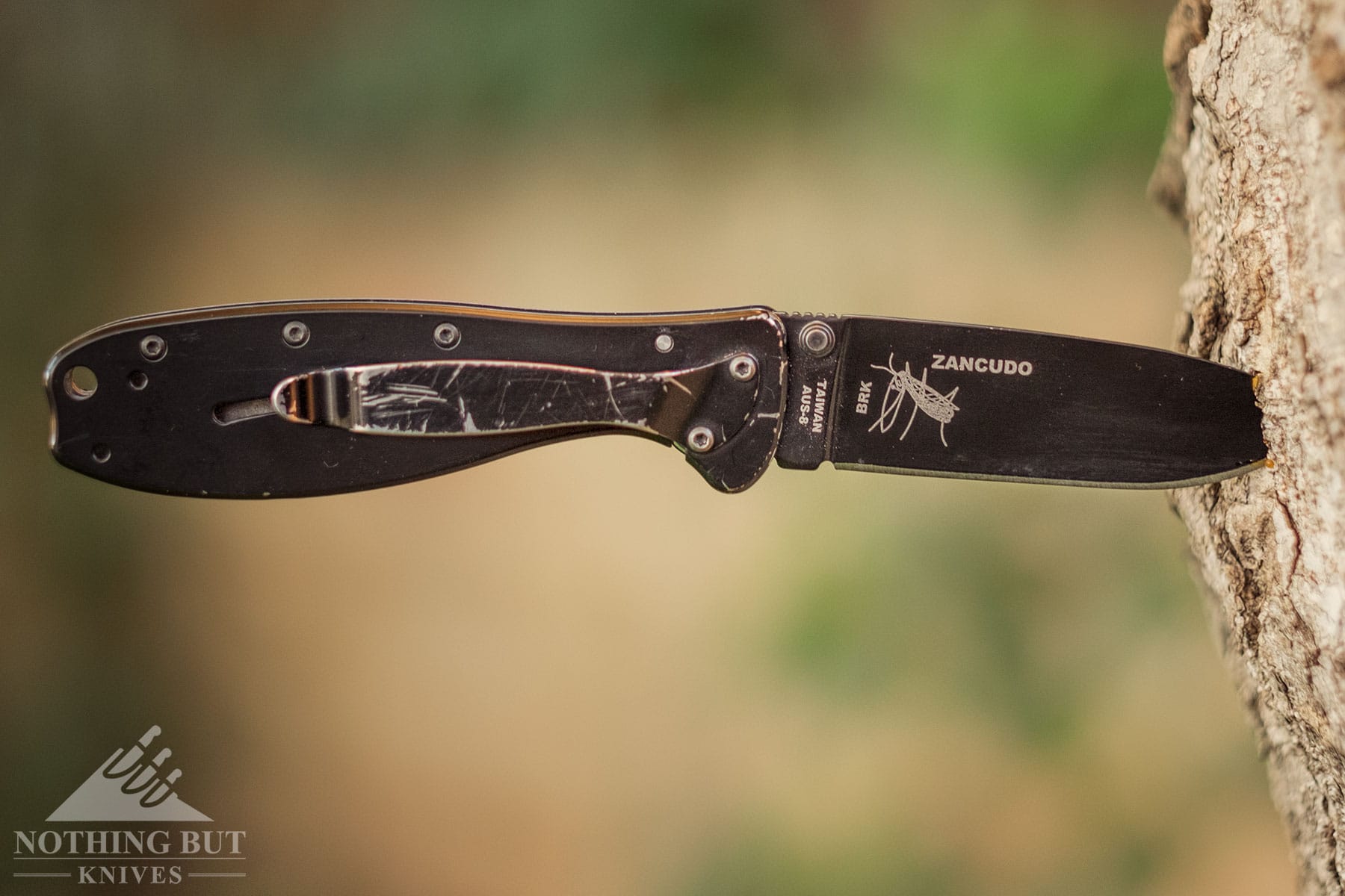 A rough looking Esee Zancudo with its blade stuck in a tree trunk. 