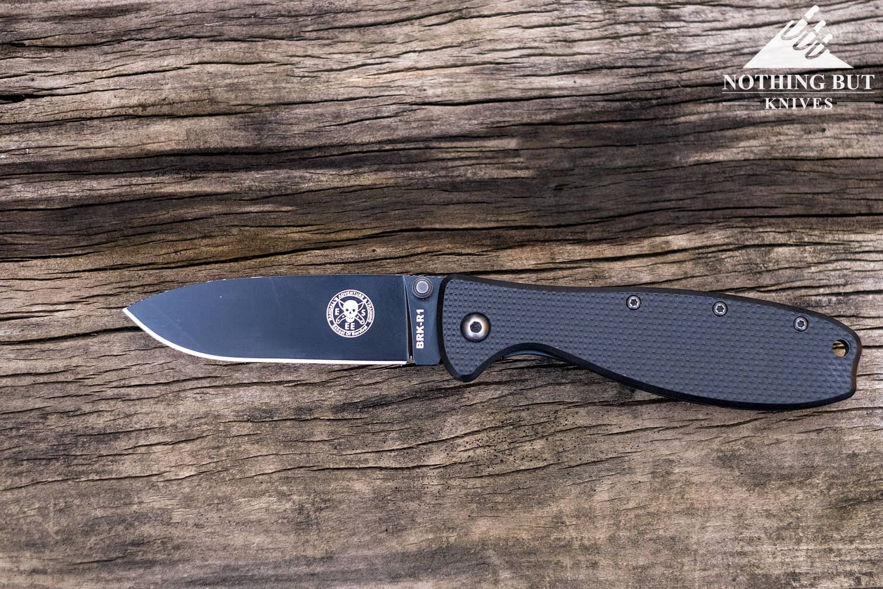 The Esee Zancudo pocket knife in the open position on a wood table. 