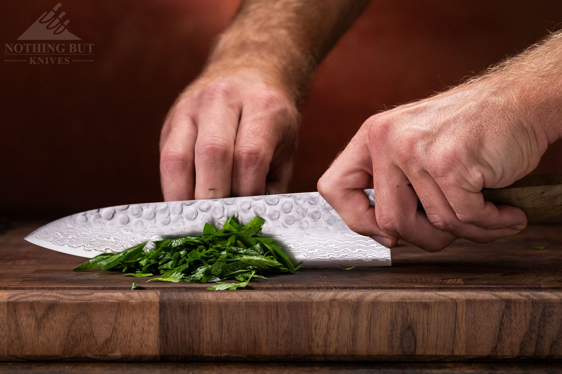 The Oishya 8 inch chef knife being used to dice onions on a wood cutting board.