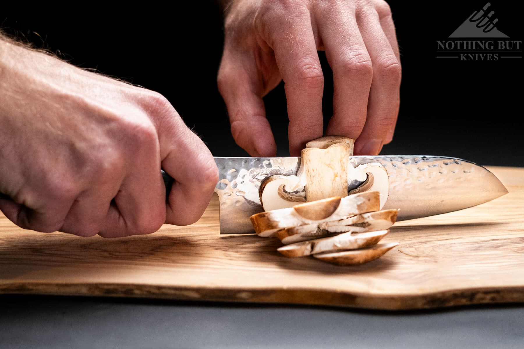 A close-up of the Enso HD santoku knife being used to slice a mushroom.
