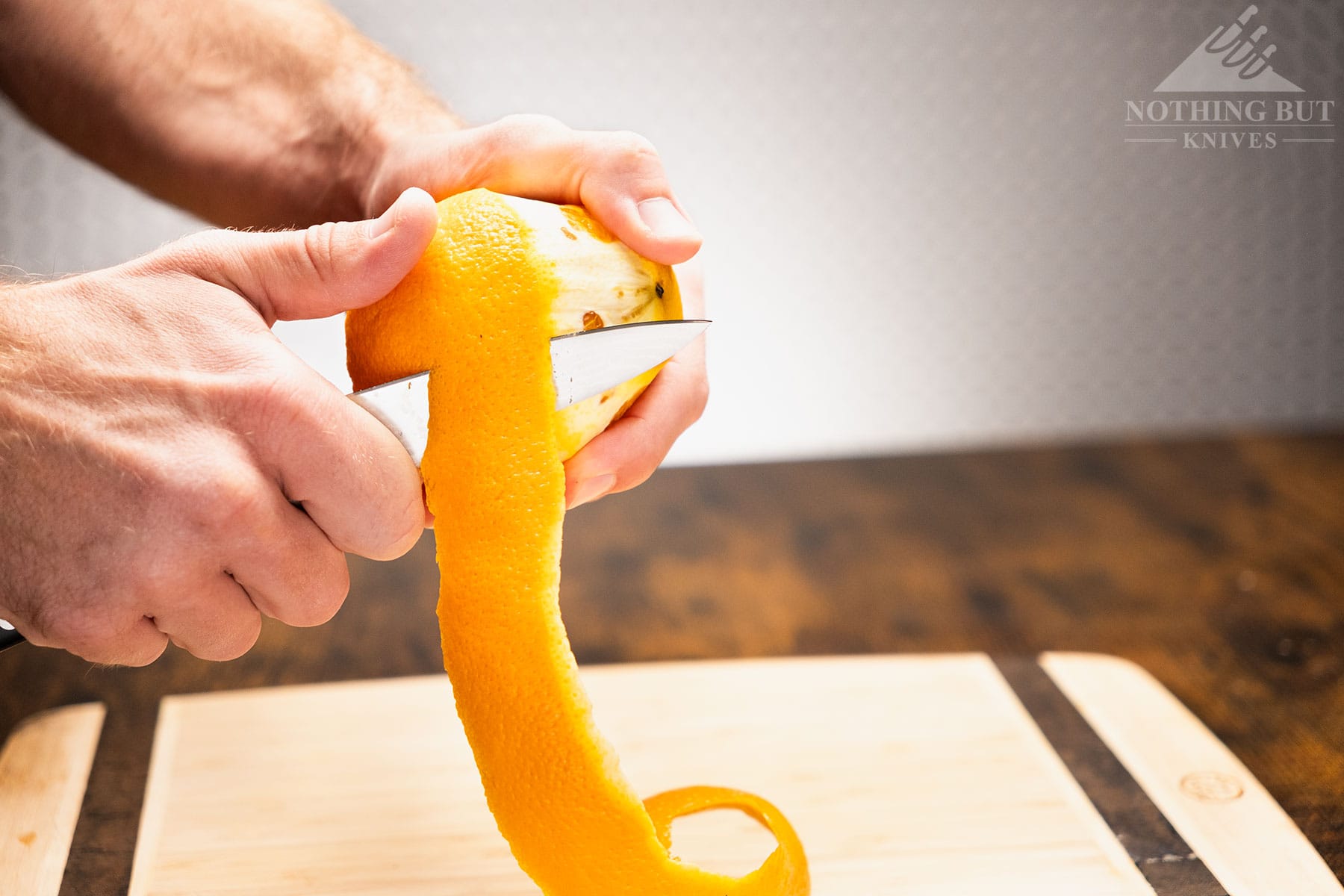 A close-up of the Tojiro DP Damascus paring knife being used to peel an orange. 