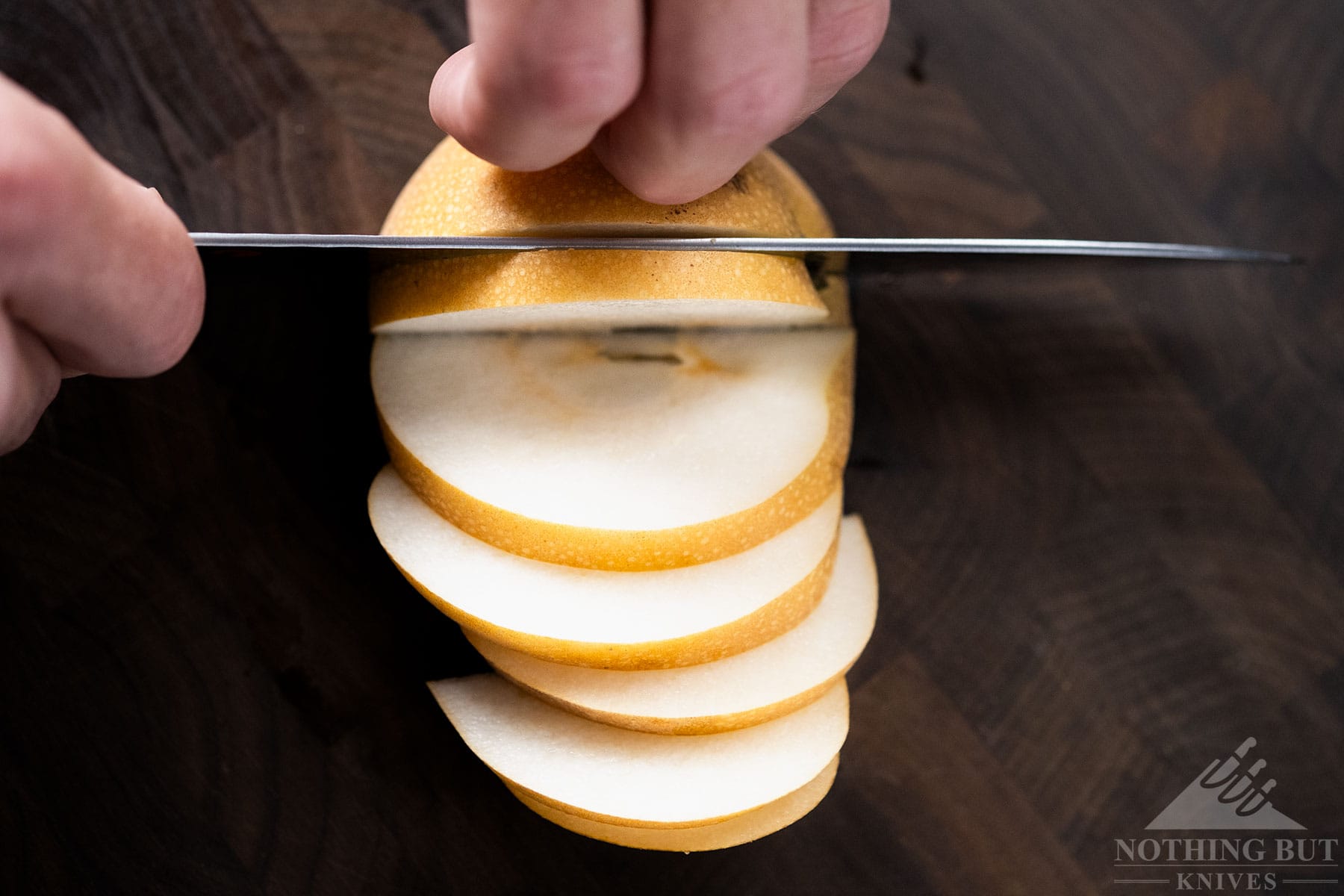 A top down view of the Miyabi Mizu SG2 chef knife slicing an Asian pear.