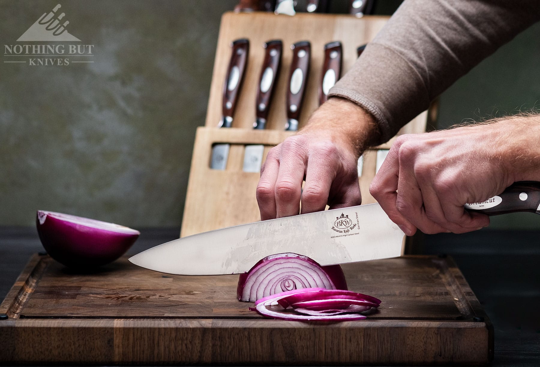 The 10 inch bread knife includes in the Bavarian Knifeworks 19-piece set shown here slicing a red tomato. 