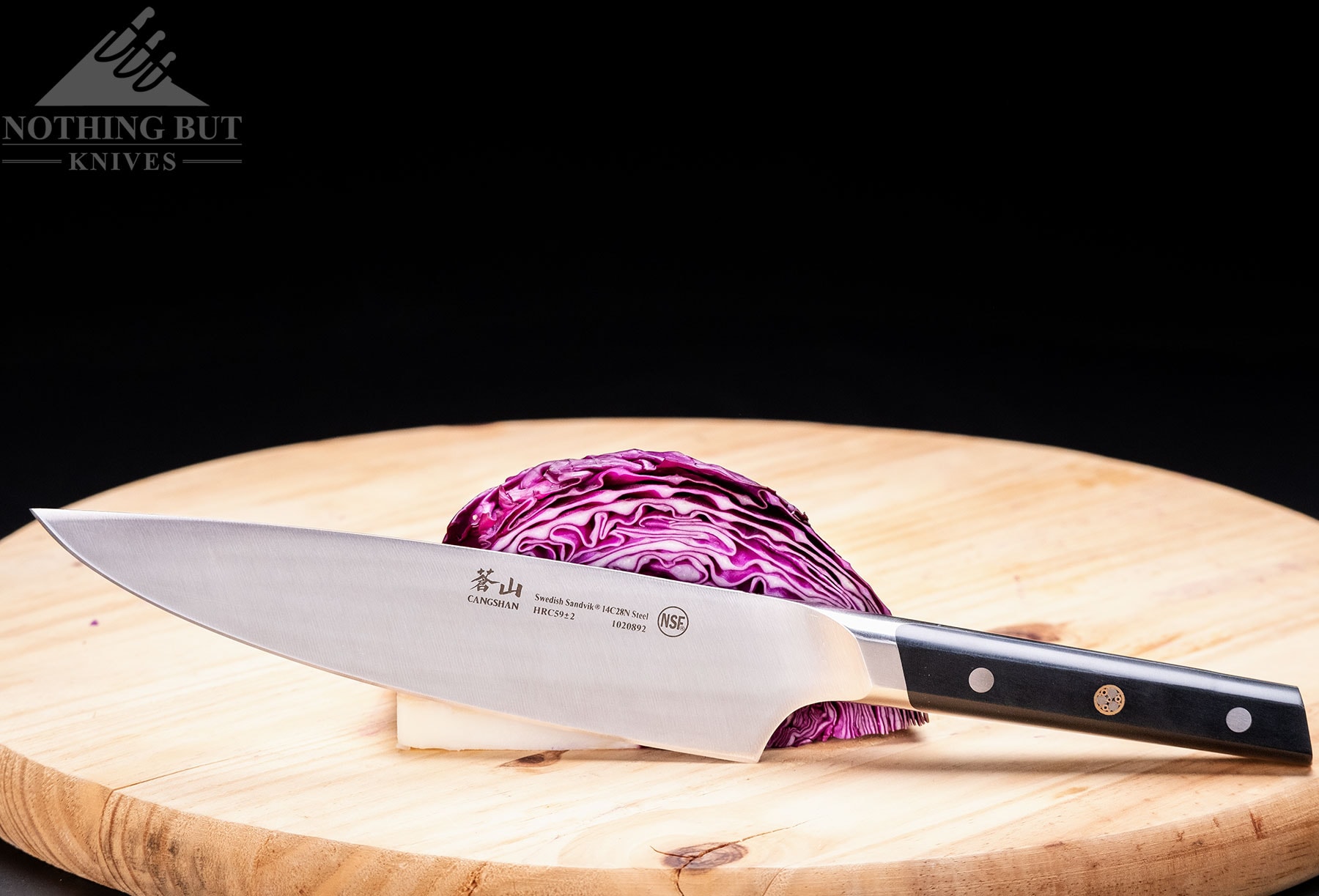 The Cangshan TC high-end chef knife leaning against a head of cabbage on a cutting board. 