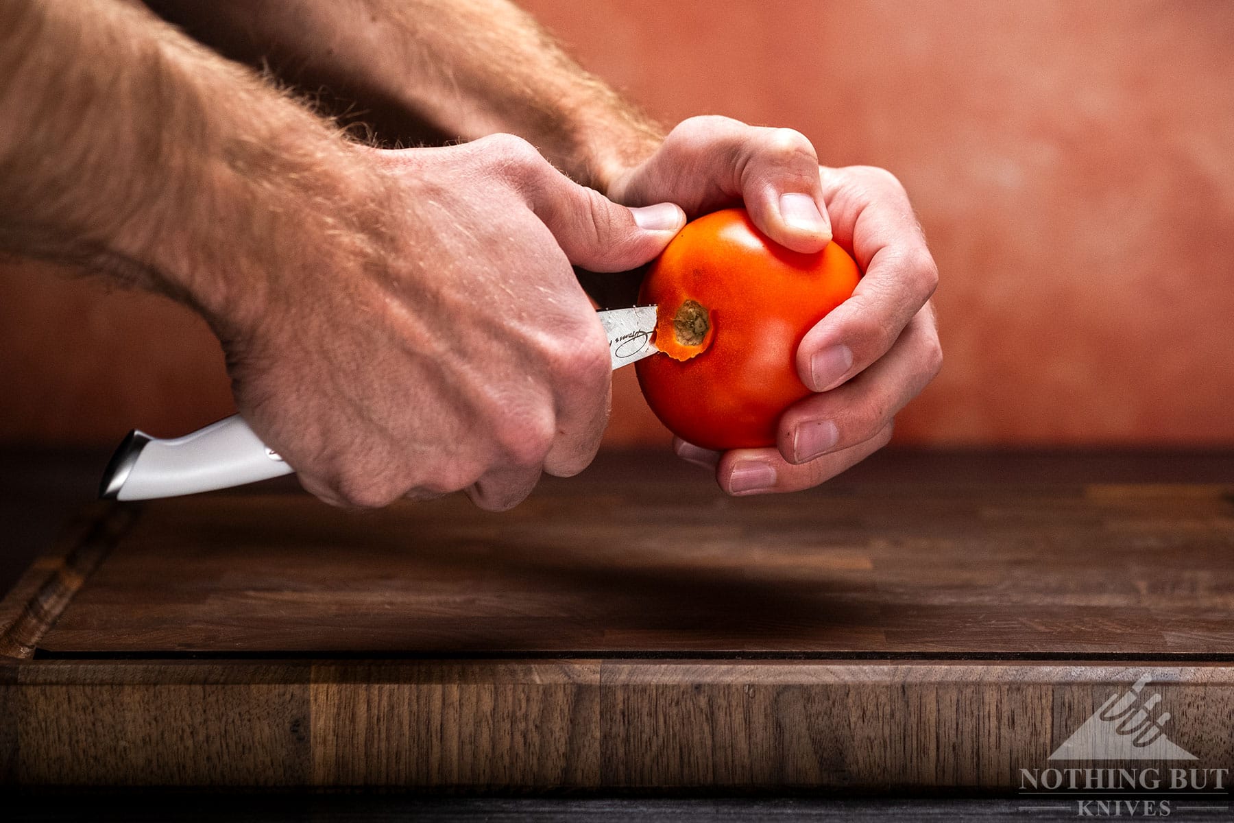 A close-up of a tomato being cored with a Cangshan Thomas Kelller paring knife.