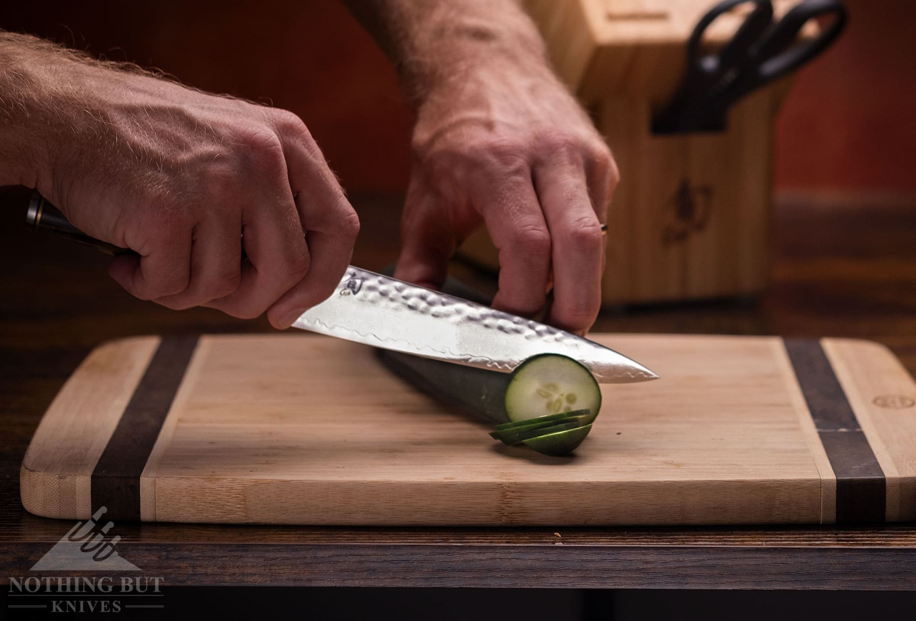 Slicing up a cucumber with the Shun Premier utility knife on a wood cutting board.