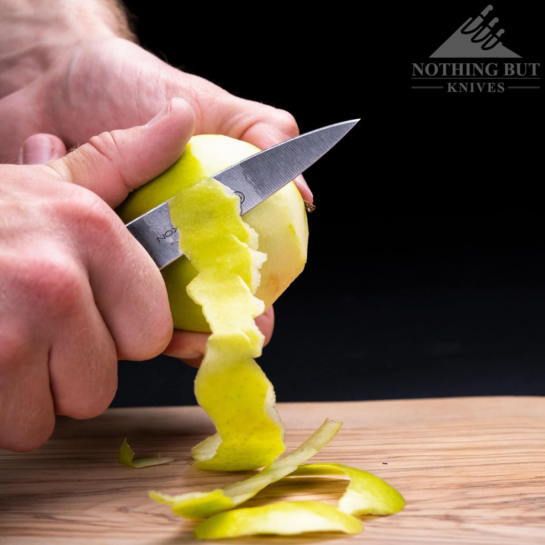 A green apple being peeled with the Wusthof Classic Ikon paring knife.