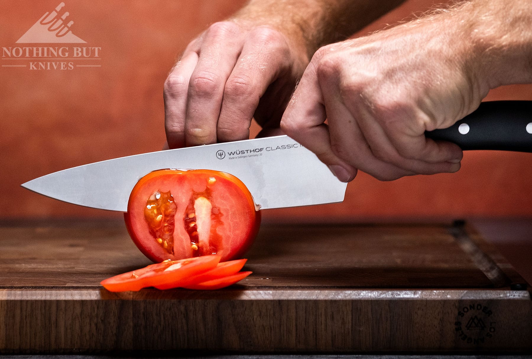 The 8-inch Wusthof Classic Ikon chef knife slicing through a tomato. 