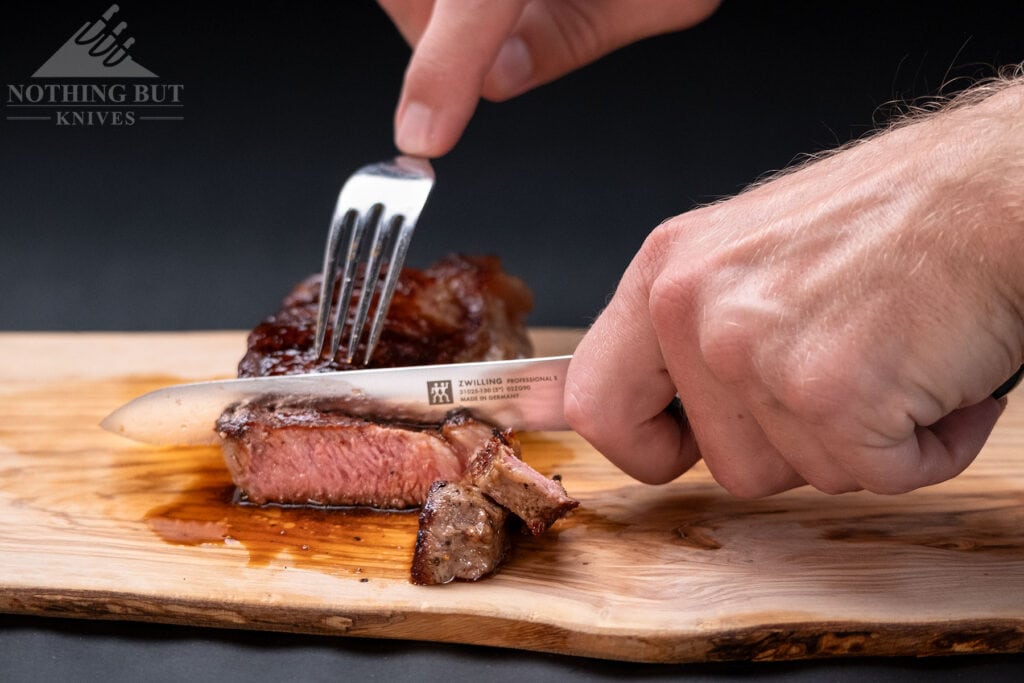 The five inch Zwilling utility knife being used to slice a piece of steak. 