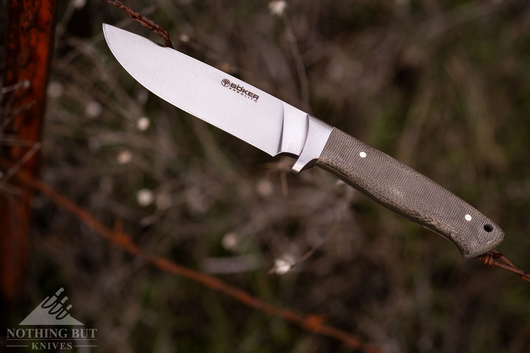 The Boker Arbolito Hunter fixed blade knife made in Argentina shown here balanced on a barbed wire fence.