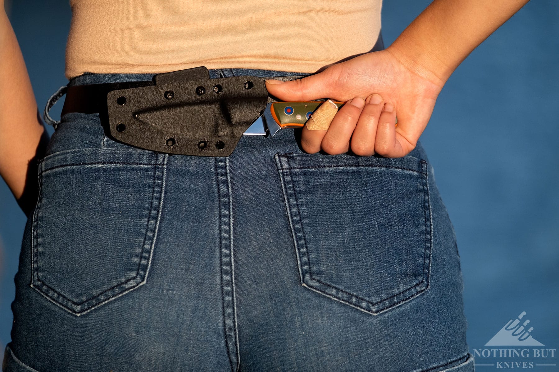The Boker Plus Brook EDC fixed blade knife being deployed from its sheath in the scout carry position on a person's waist.
