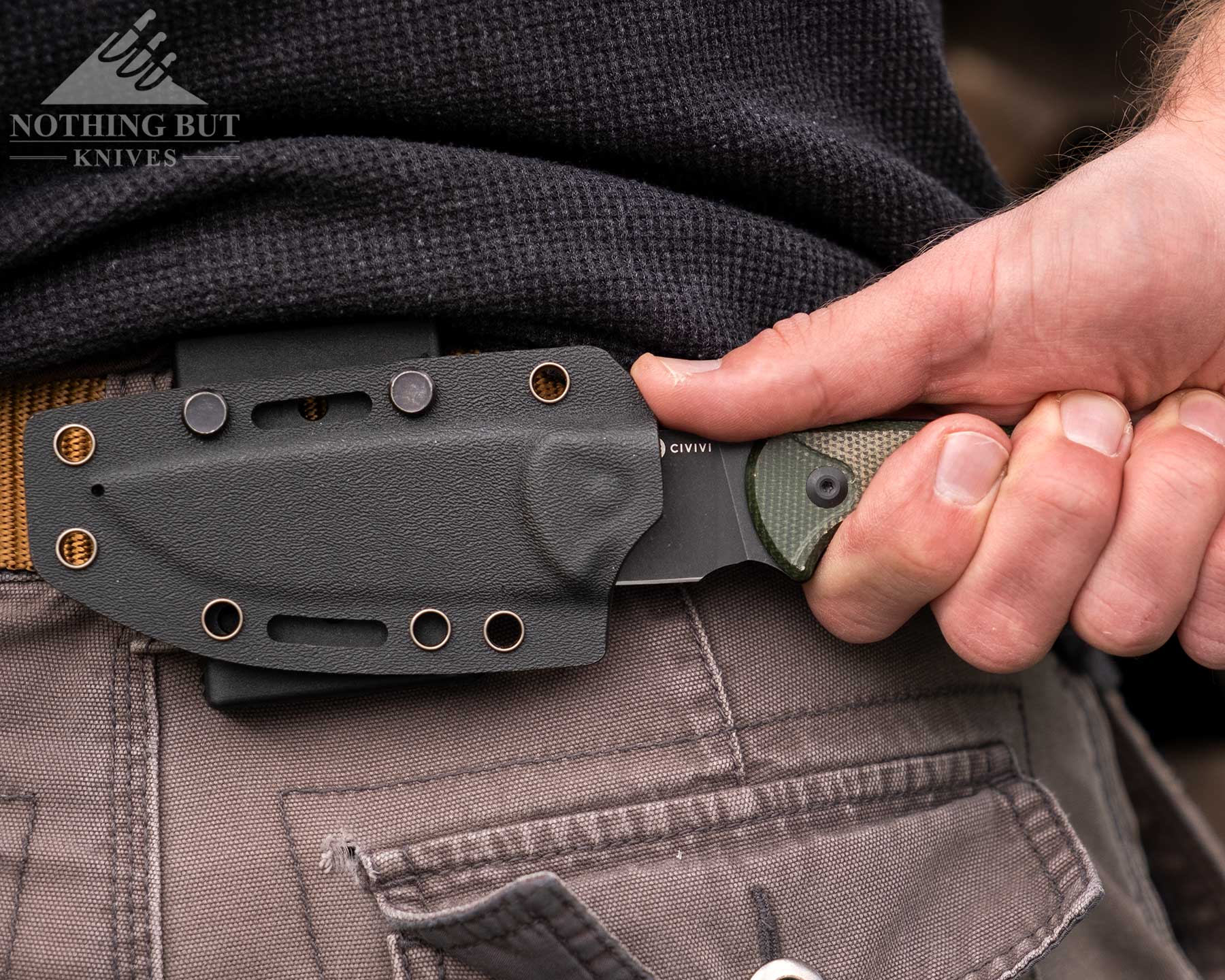 A close-up of a person's hand deploying the Civivi Timberbark from its horizontal carry pancake style kydex sheath. 