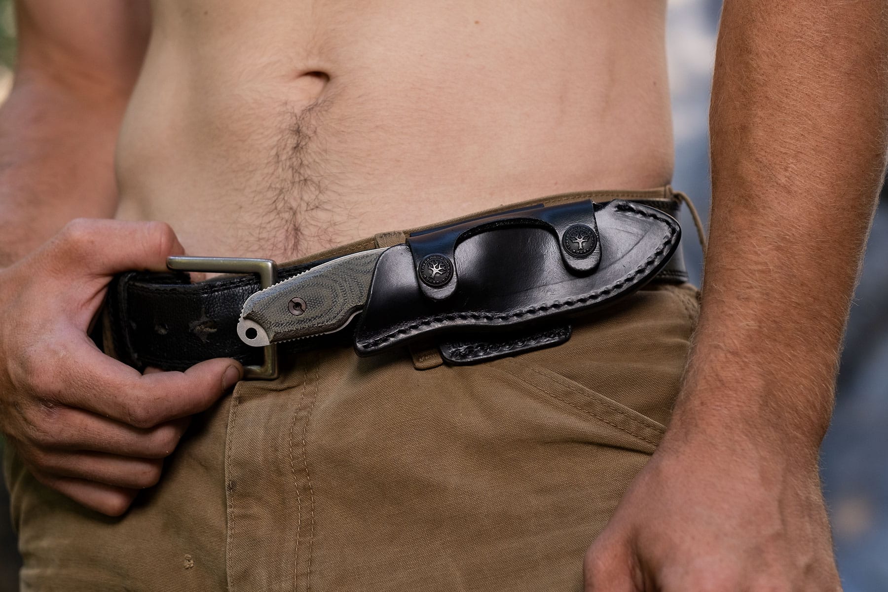 The Boker Arbolito El Heroe fixed blade knife in its leather sheath on a person's hip in the front horizontal carry position.