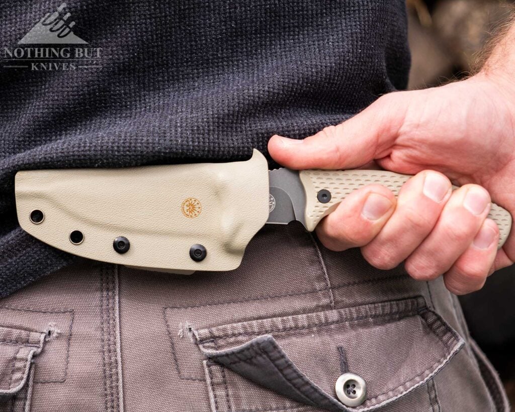 The Off-Grid Sidekick set up for scout style horizontal carry in the small of a person's back in front of a woodpile. 