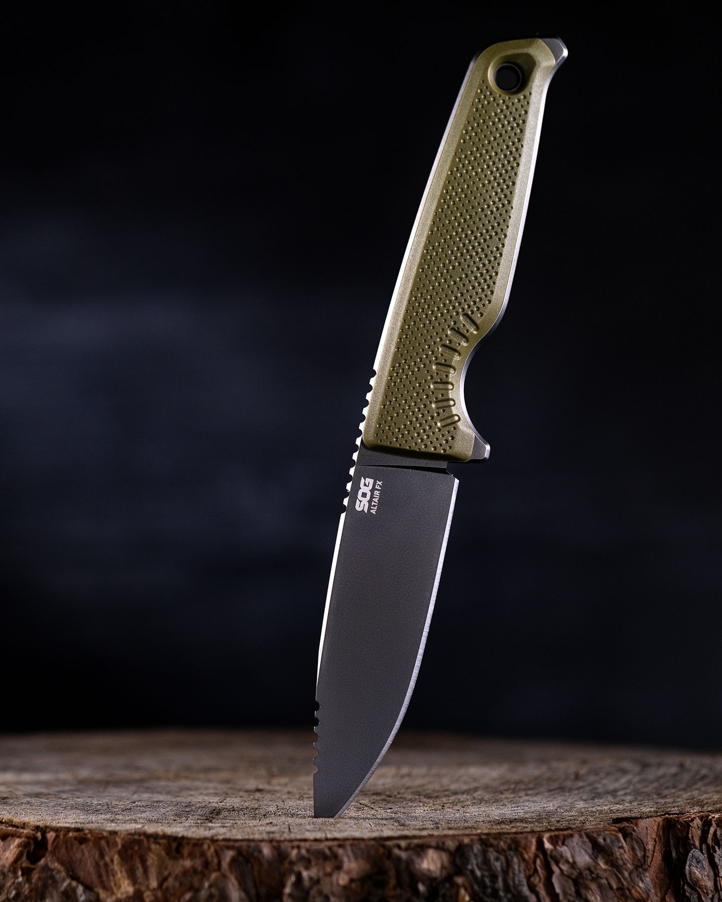 The American made SOG Altair fixed blade knife with its blade tip stuck into a tree stump in front of a black background.