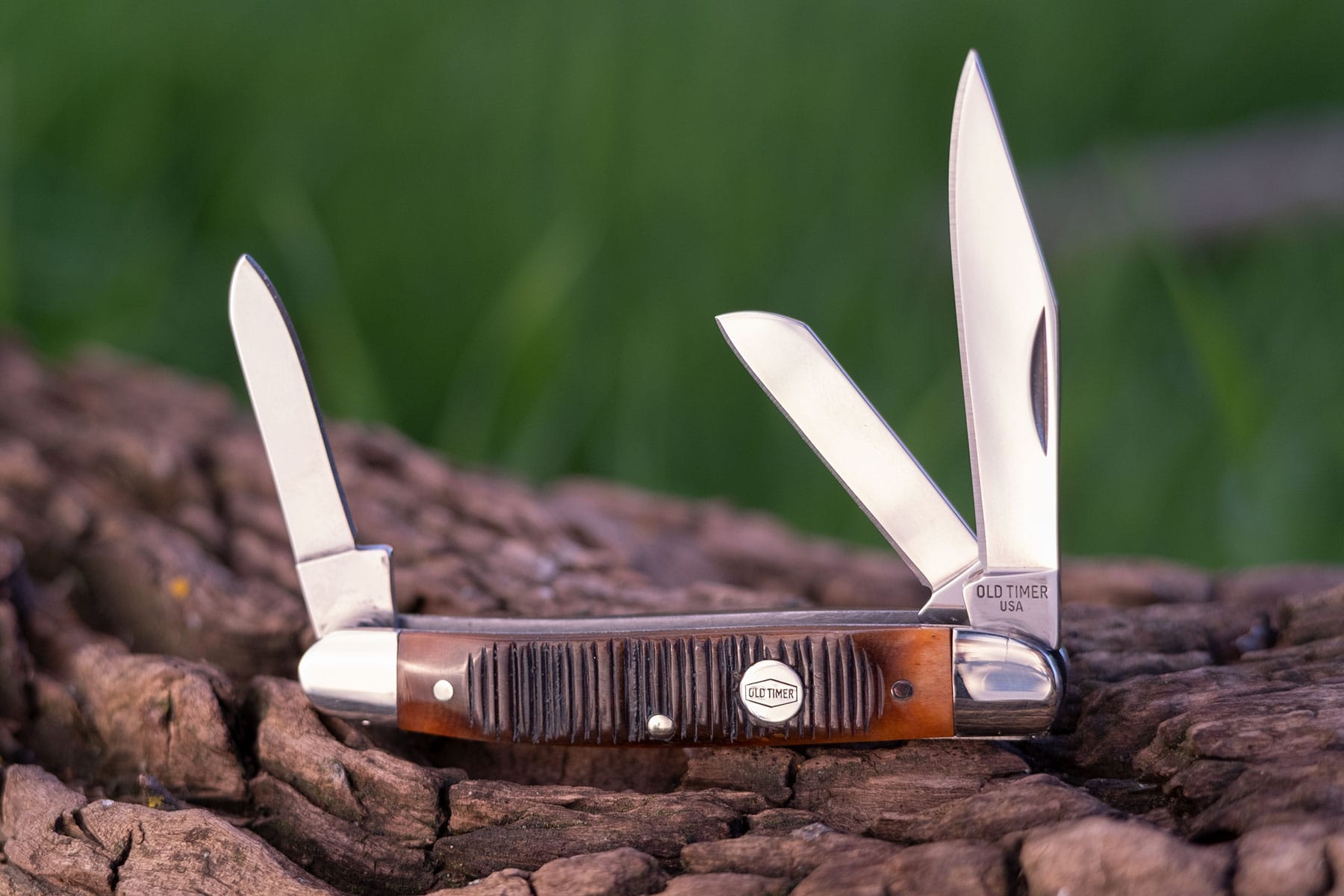 The Schrade Middleman Generational Series slip joint knife shown here with all three blades in the open position on a tree branch outdoors.