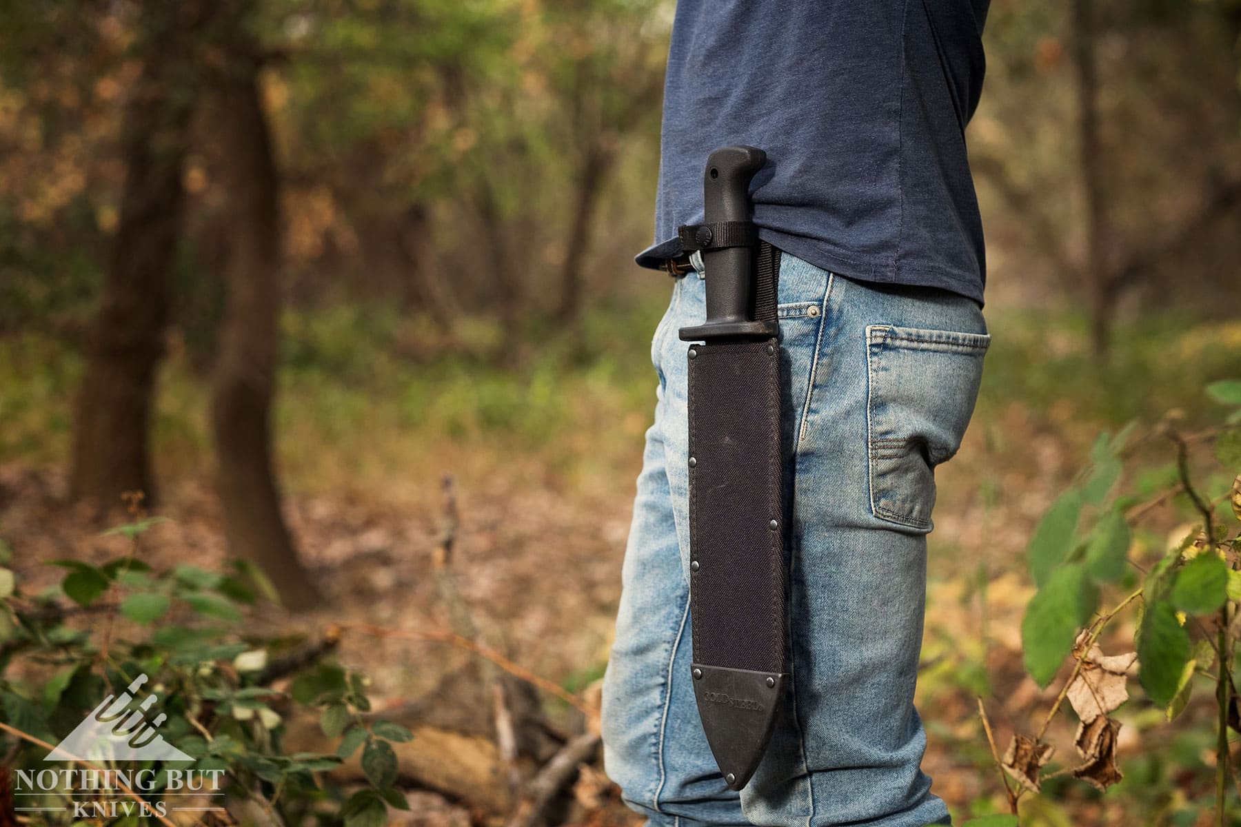 The Black Bear Bowie knife in its sheath on a person's hip.