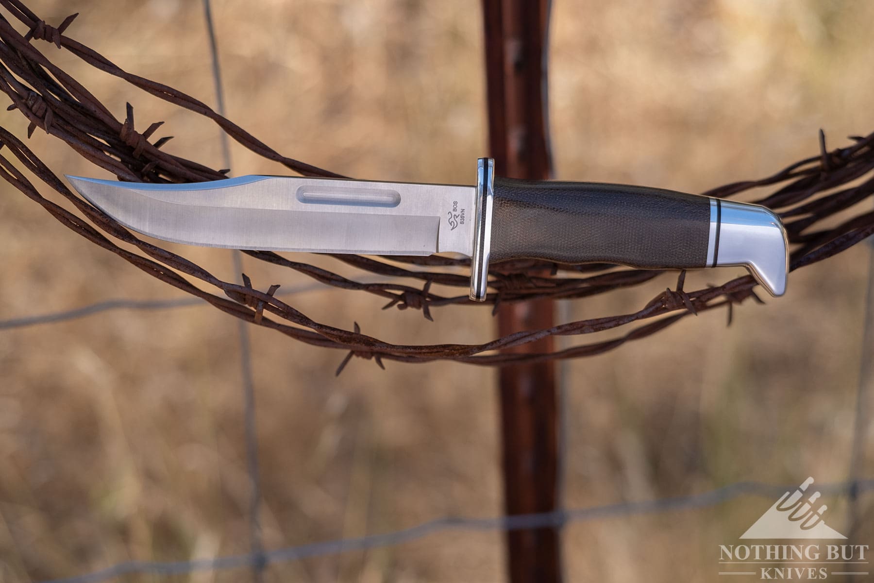 The Buck 119 Special balanced on a roll of barbed wire hanging from a fencepost.  