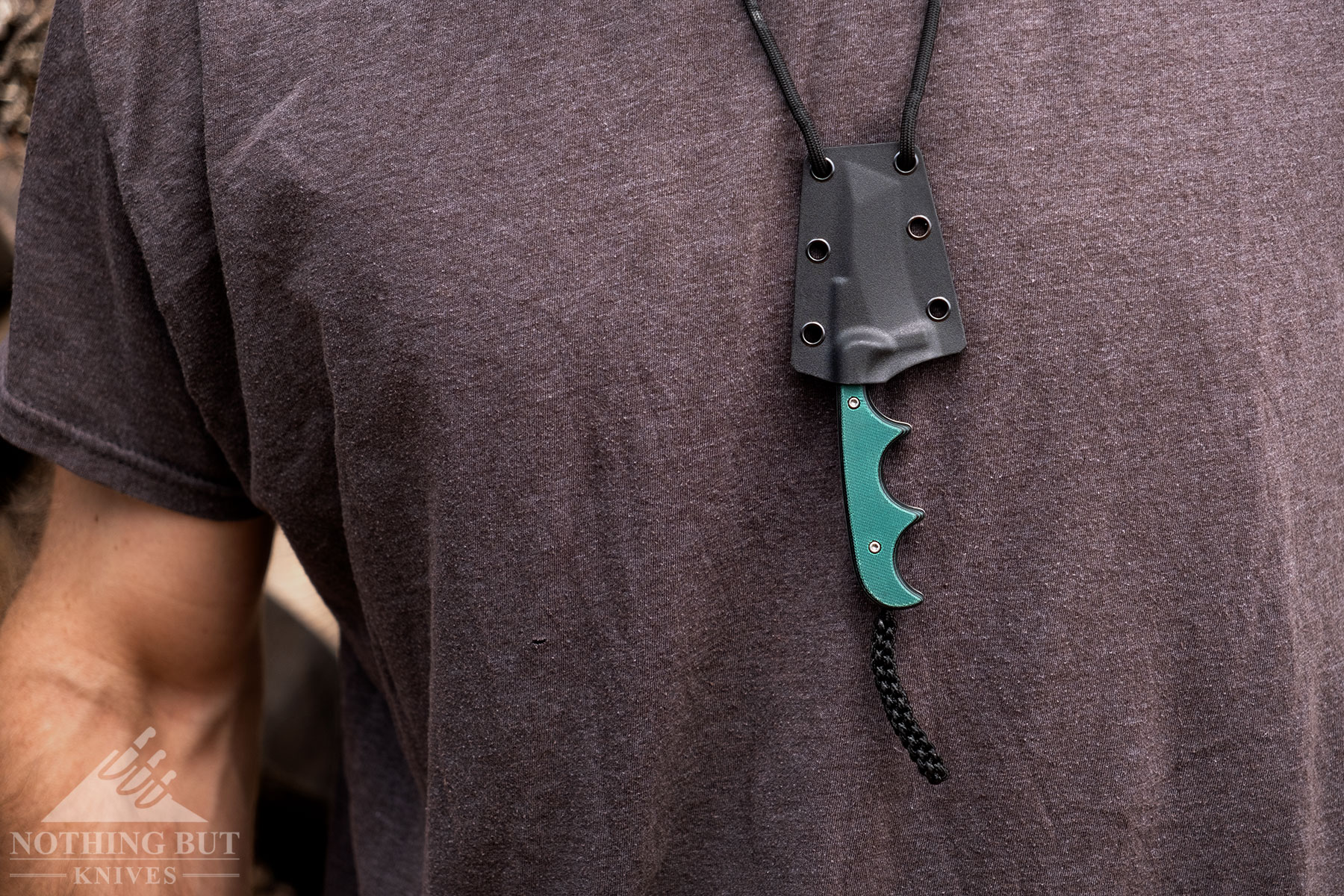 The CRKT Minimalist fixed blade knife in its sheath hanging on a lanyard around a person's neck.