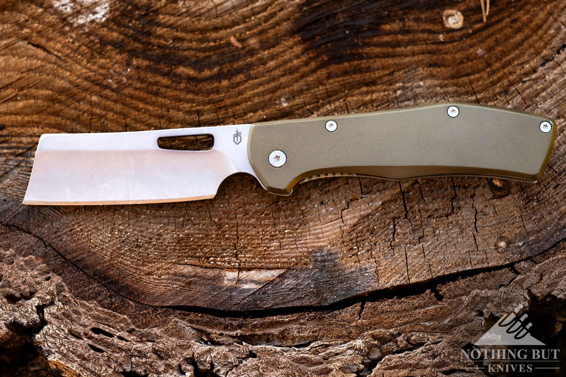 The Gerber Flatioron pocket cleaver with the blade in the open position on top of a tree stump. 