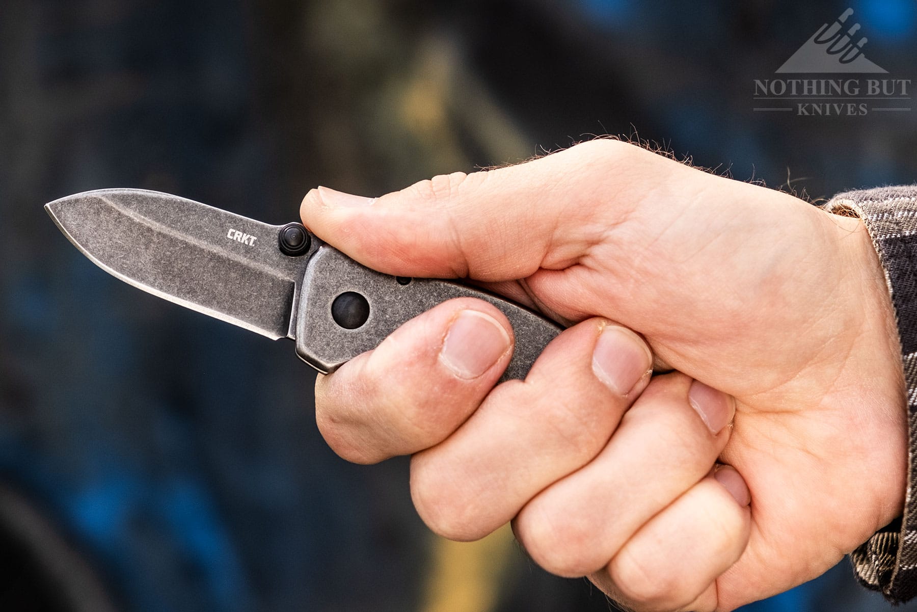 A close-up of the CRKT Squid with the blade open being gripped via its stainless-steel handle in a person's right hand. 