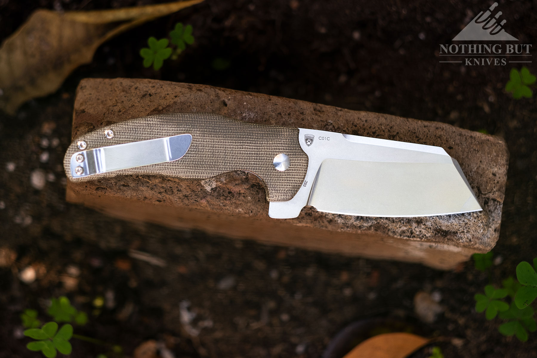 The Kizer Sheepdog hard-use folder shown here with the blade in the open position on top of a brick outdoors.