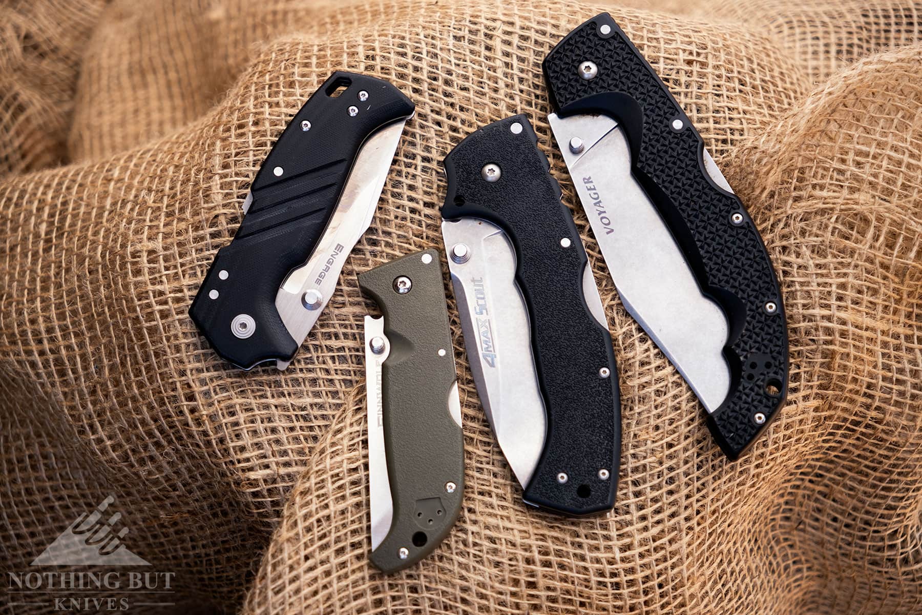Four pocketknives in the closed position on burlap.