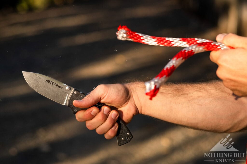 A close-up of the Cold Steel 4Max Scout slicing through a red and white rope. 