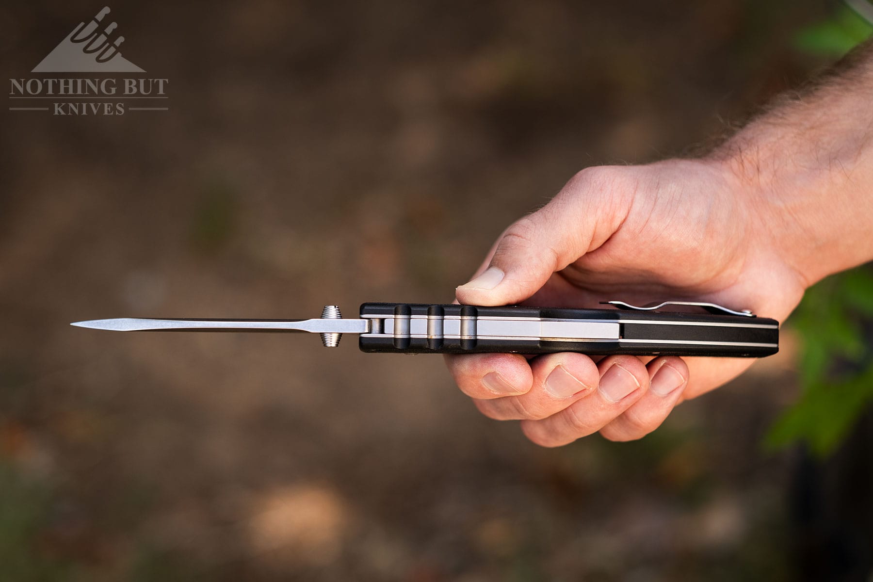 The 4-MAX Scout being held in a person's hand with the top of the knife facing the camera to show the overall thickness.
