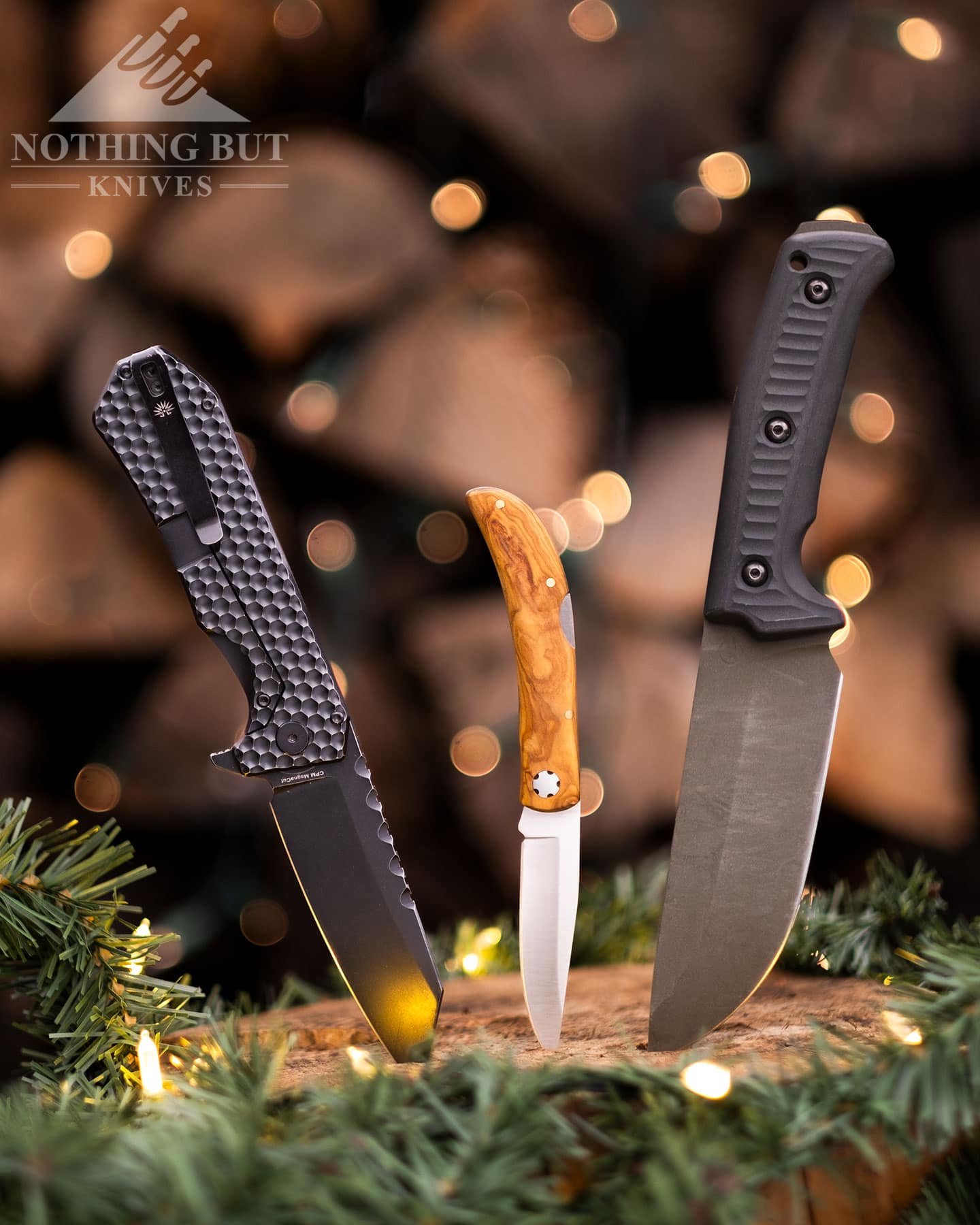 Three great knives for gift options in 2024 sticking out of a tree stump that is decorated for the holidays.