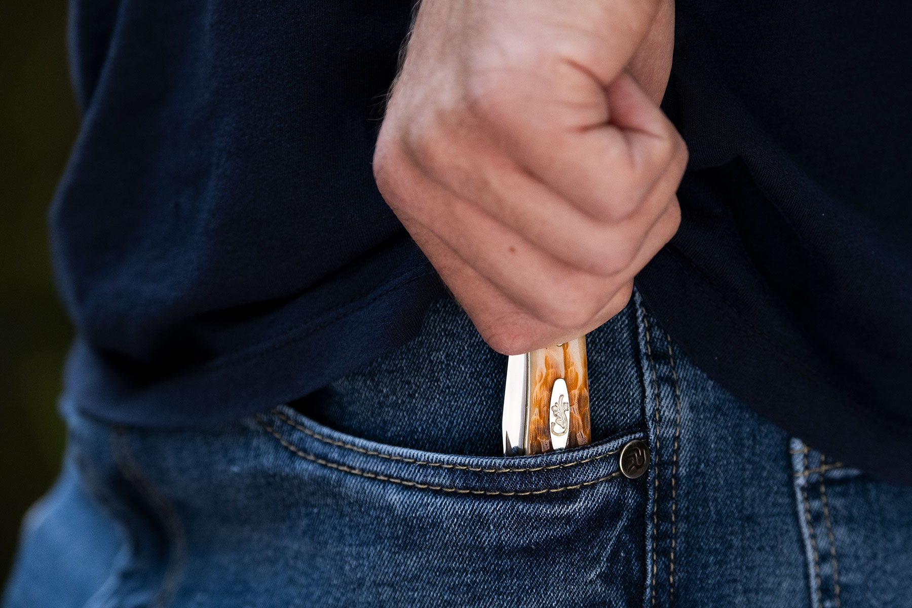 A close up of a person's hand pulling the Case Trapper slip joint from the left front pocket of jeans.