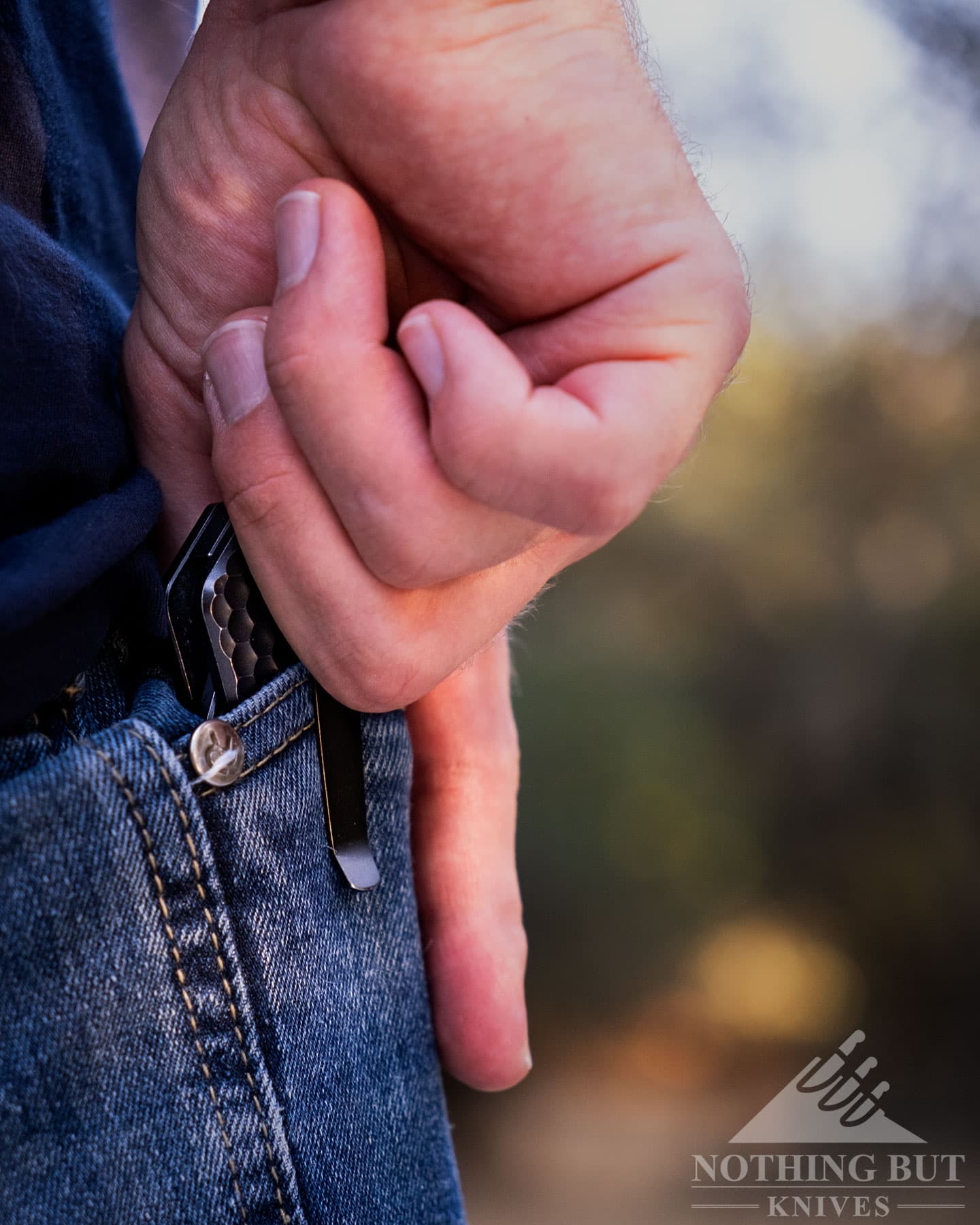 A close-up of the Off-Grid Black Mamba V3 knife being pulled from a pocket of a person's blue jeans.