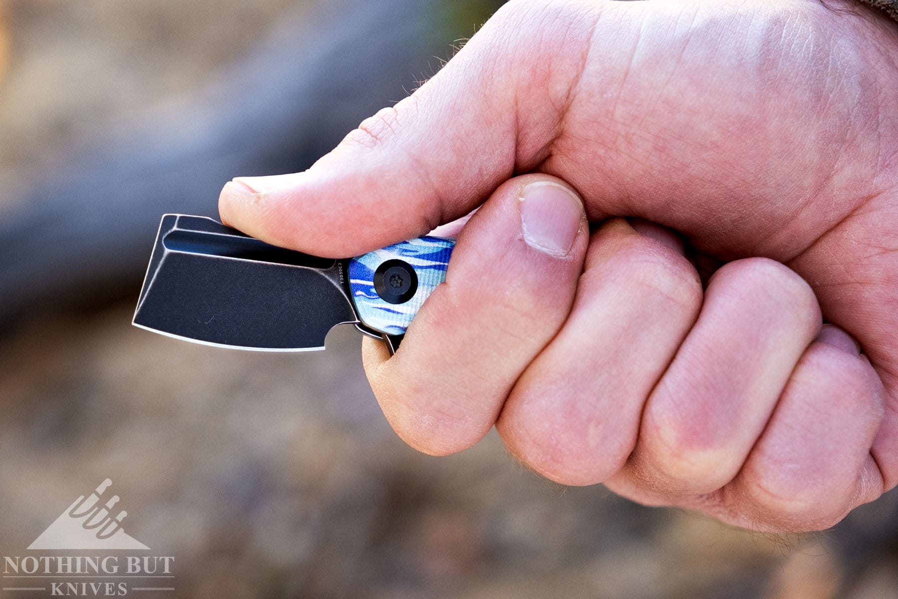 A person's right hand gripping the kansept Mini Korvid Ice pocket knife. 