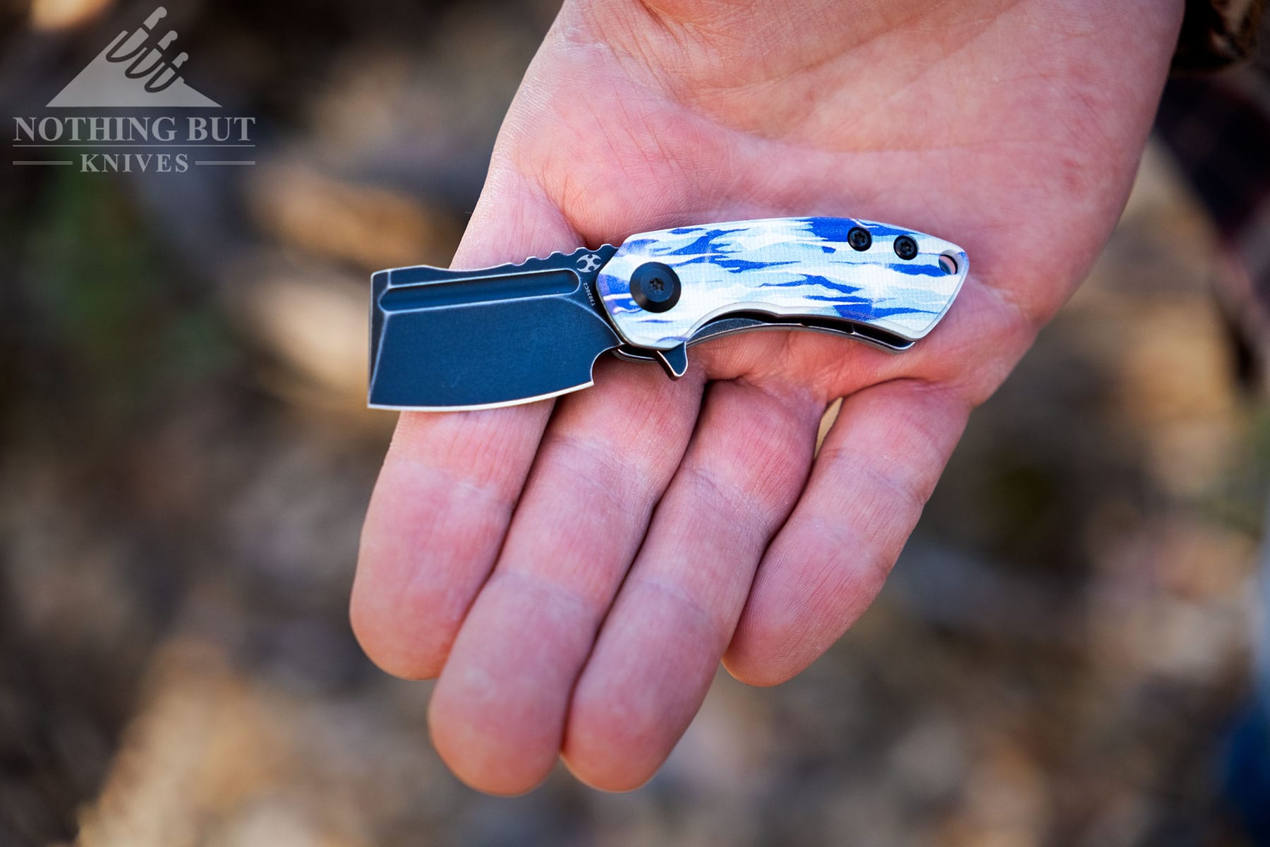 The Kansept Mini Korvid Ice folding knife in the open palm of a person's hand to show scale. 