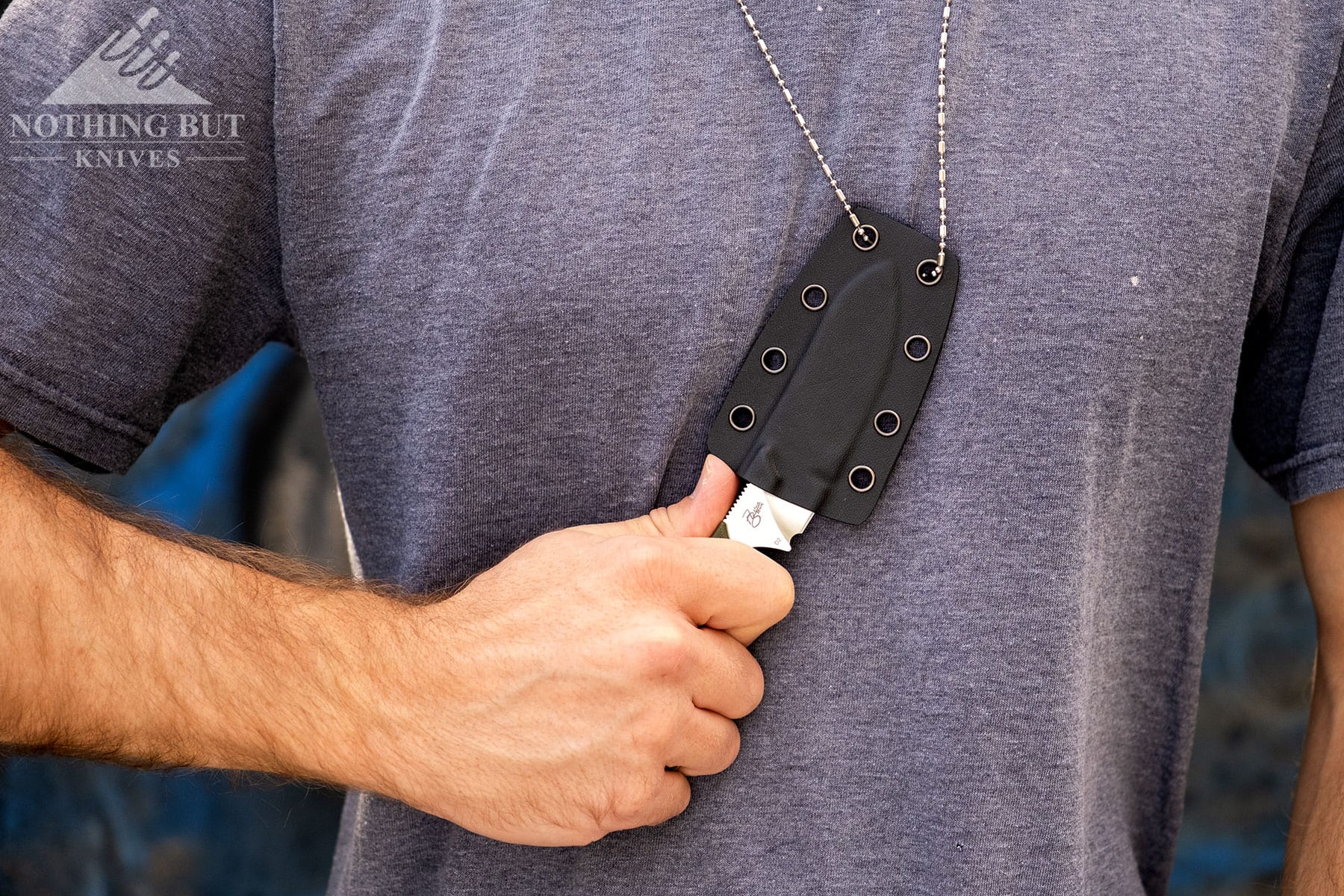 A close-up of the QSP Neckmuk being frawn from its sheath while being worn as a neck knife. 