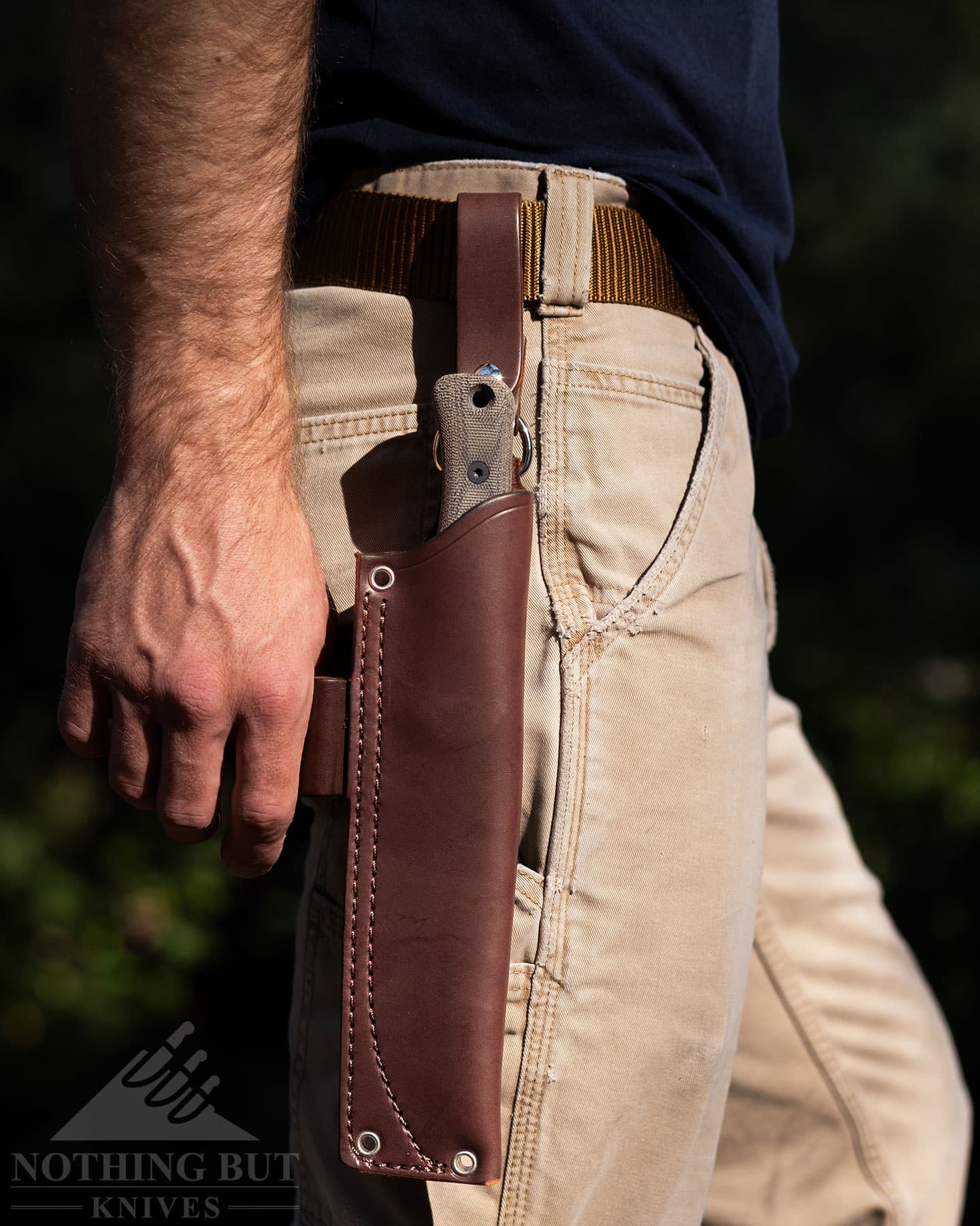 The Reiff F6 Leuko knife in its sheath attached to a leather belt on a person's waist. 