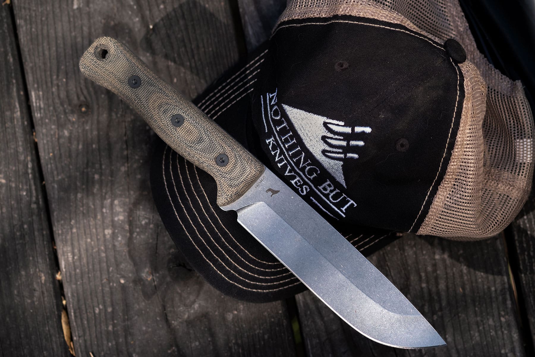 The Reiff F6 knife with a Magnacut blade sitting on a Nothing But Knives hat on top of a picnic table.   