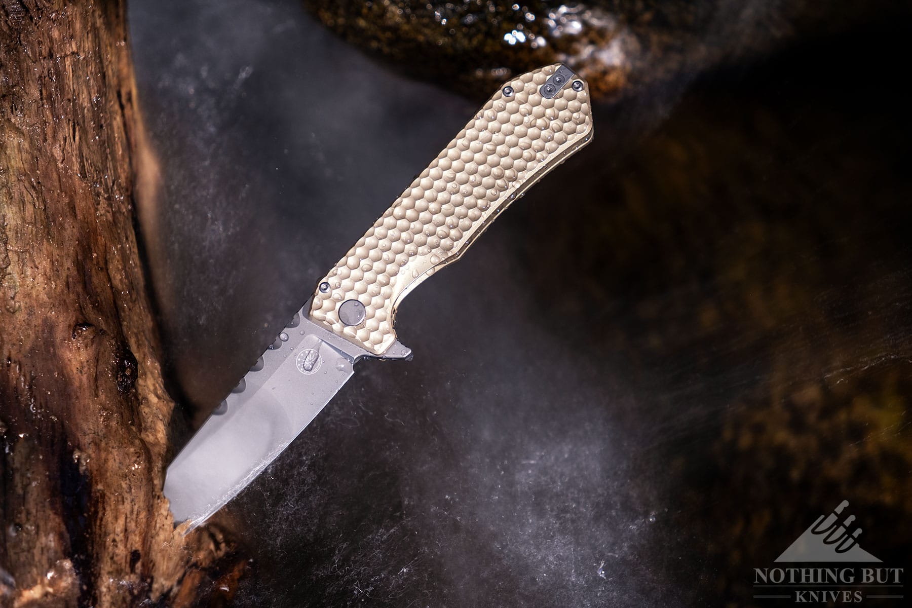 The Coyote Gold version of the Off-Grid Black Mamba V3 sticking out of a piece of driftwood in a mountain creek. 