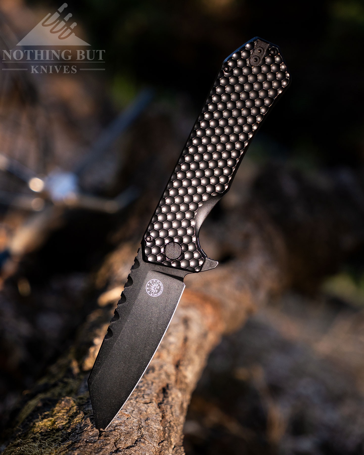 The Off-Grid Black Mamba V3 folding knife with its blade open sticking out of a log with the handle profile towards the camera. 