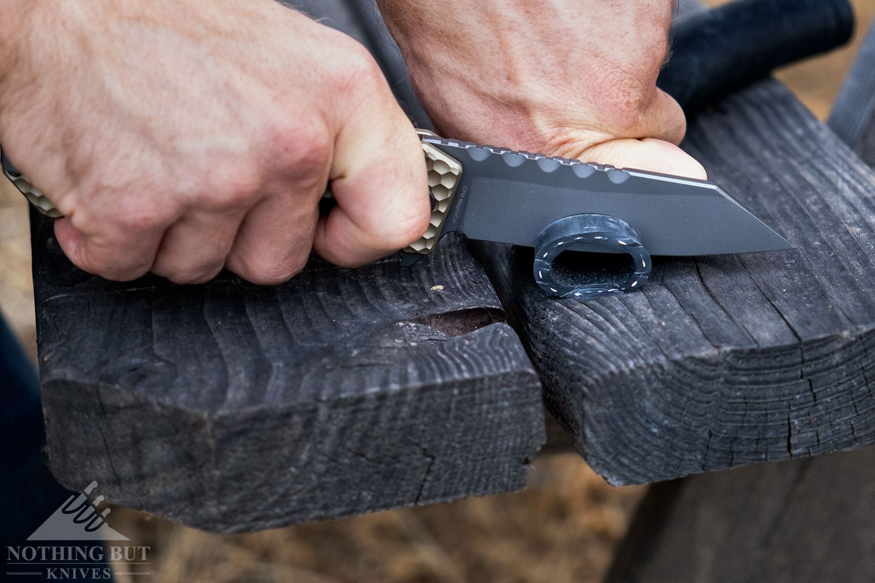 The Off-Grid Black Mamba V3 pocket knife being used to slice a length of rubber tubing. 