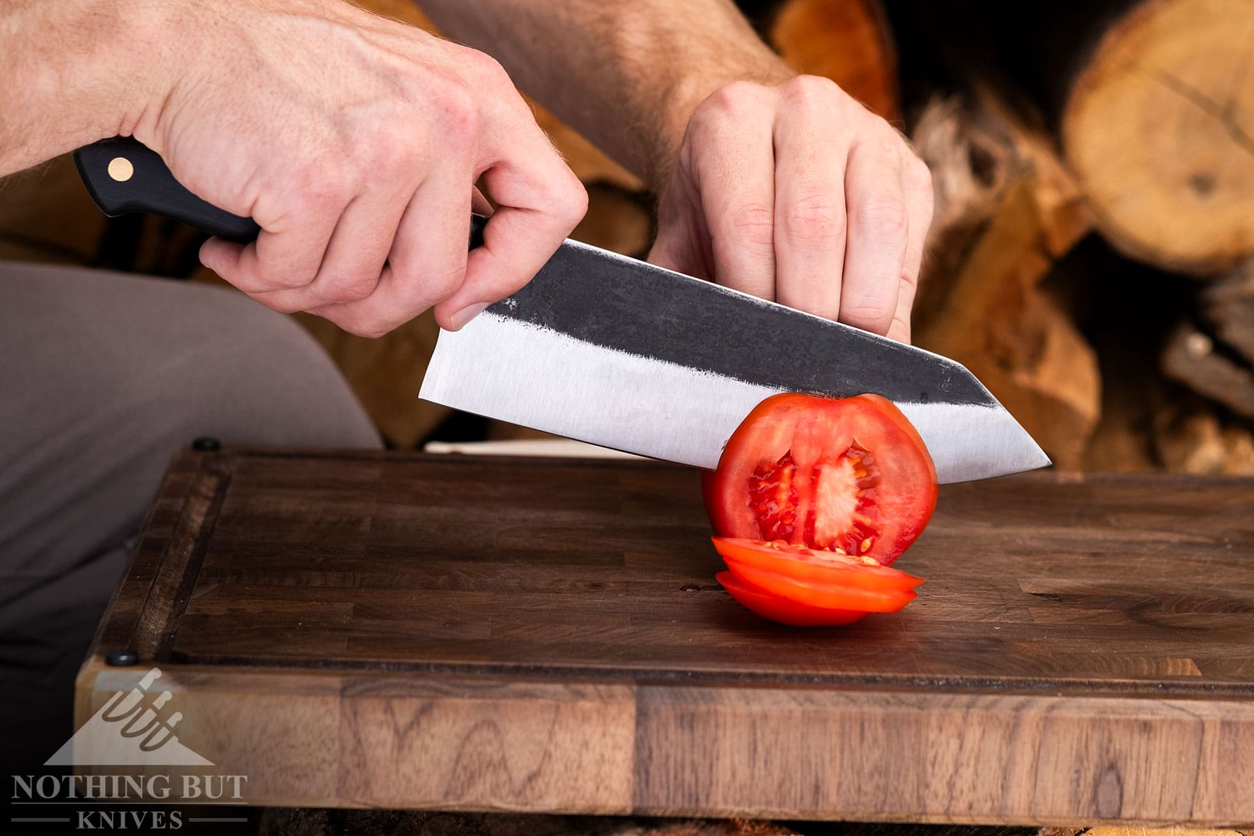 Slicing a tomato with the Kitchen Perfection chef knife outdoors.