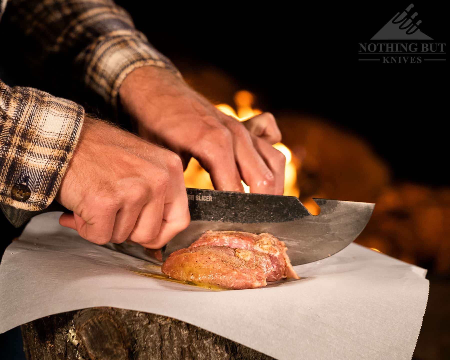 Slicing meat next to a campfire with the Condor Bush Slicer.