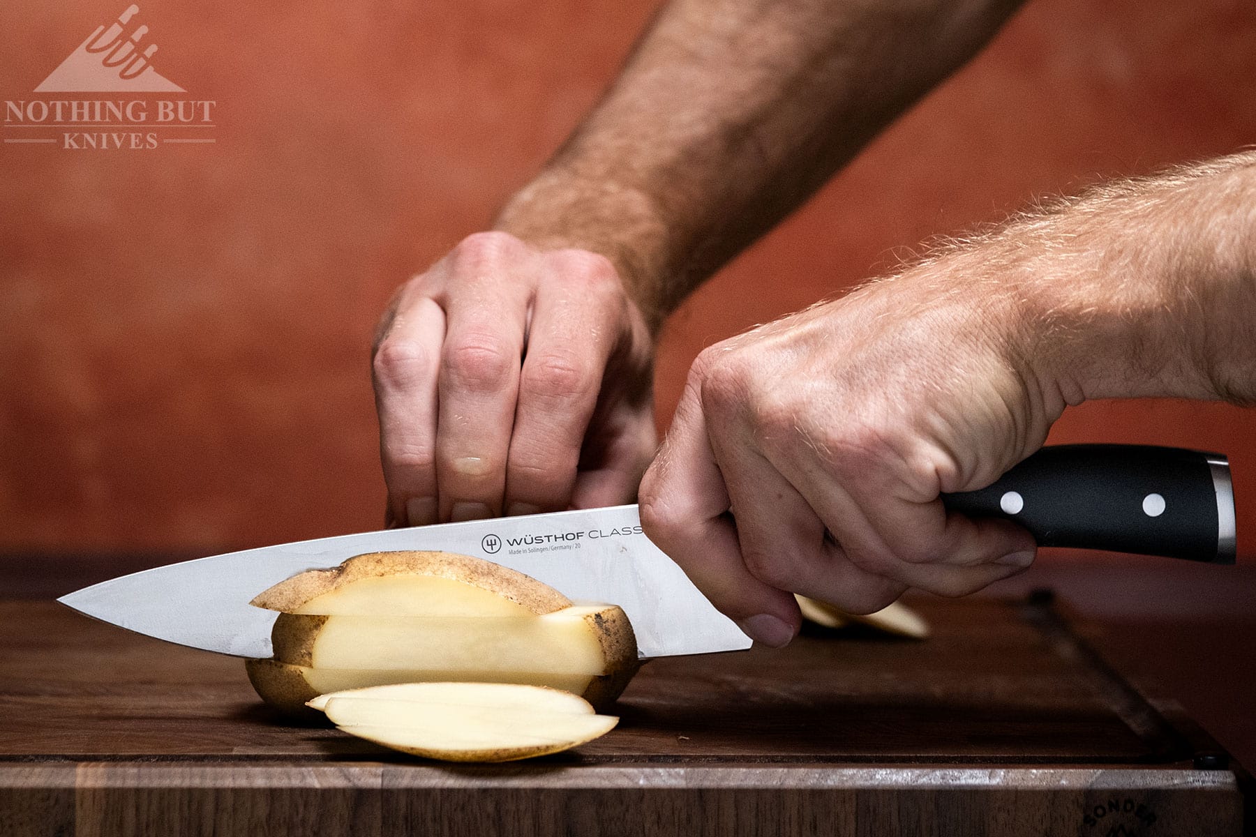A close-up of the Wusthof Classic Ikon chef knife being used to dice a potato. 