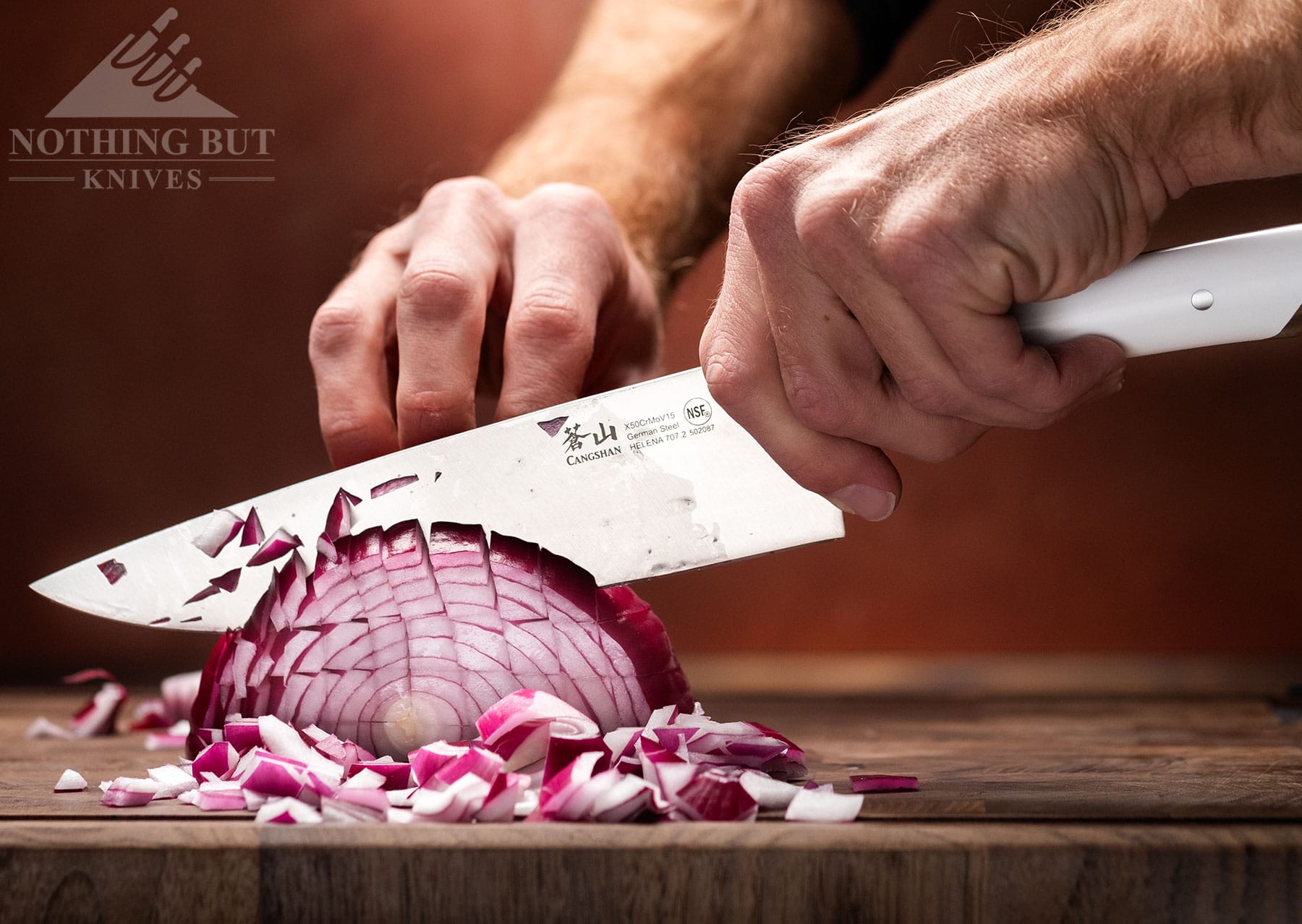 A close-up of the Cangshan Helena 8 inch chef knife dicing a red onion.