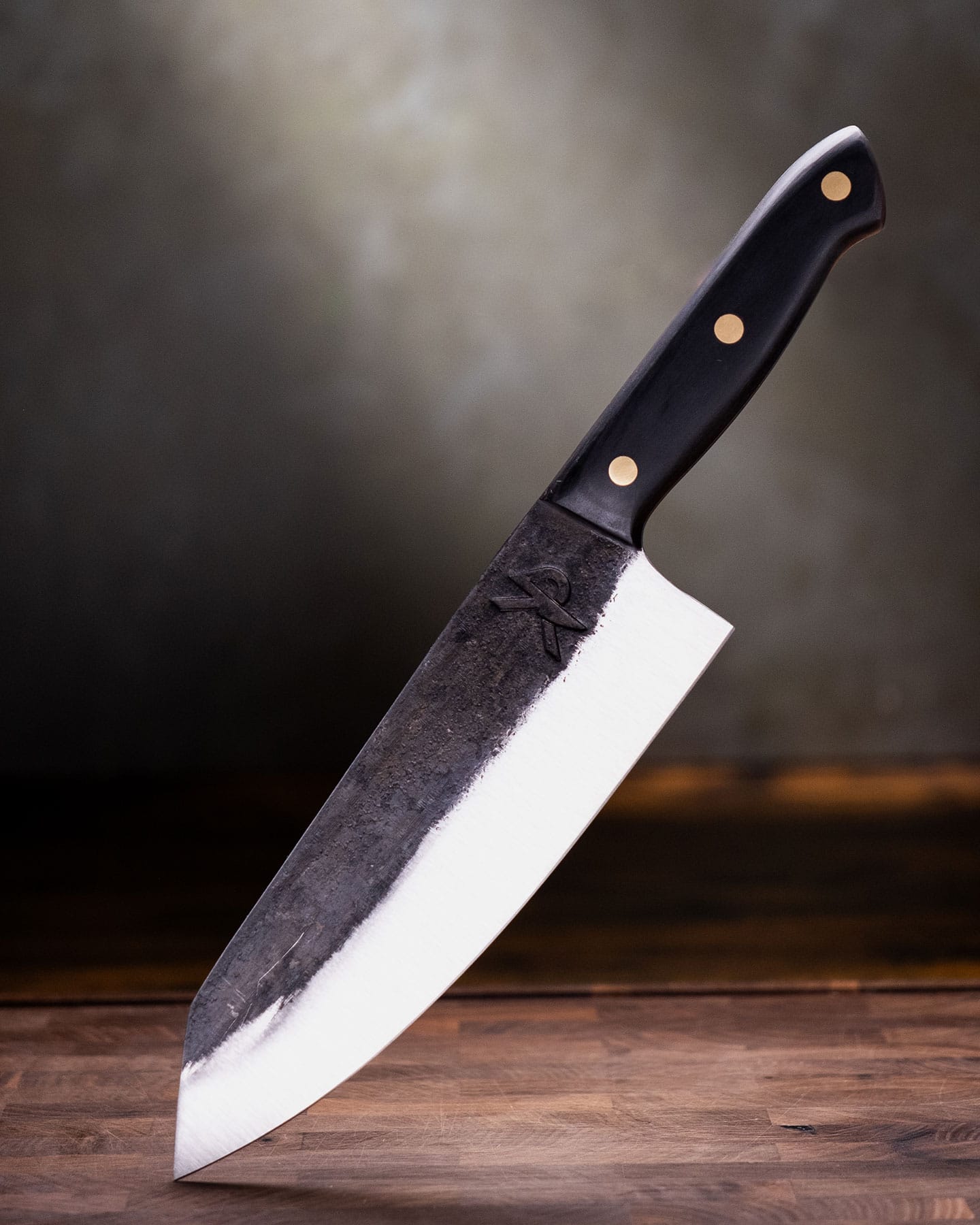 The Kitchen Perfection chef knife on a wood cutting board in front of a green background.