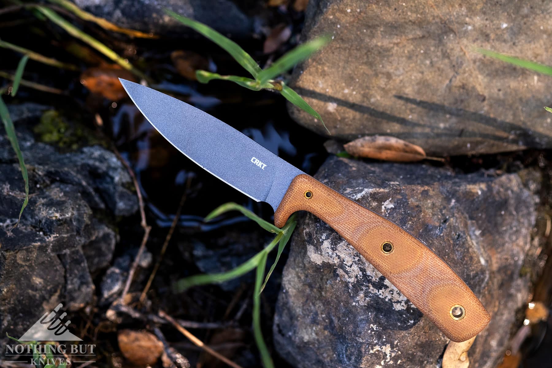 The CRKT Soldotna sitting on a rock next to a creek in the wilderness.