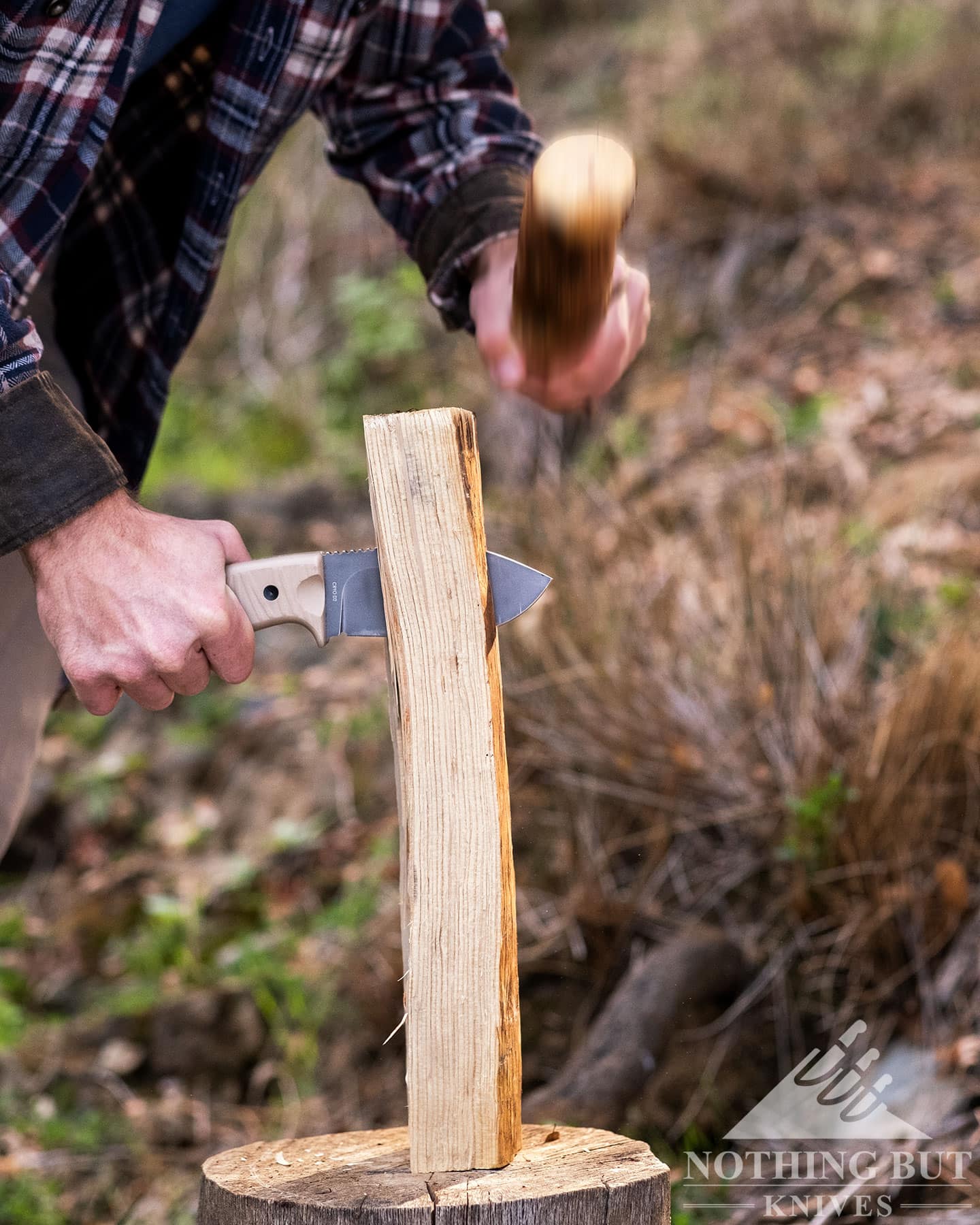 The Off-Grid Alpha-Dog being used to baton a piece of firewood to show the toughness of the D2 steel blade.