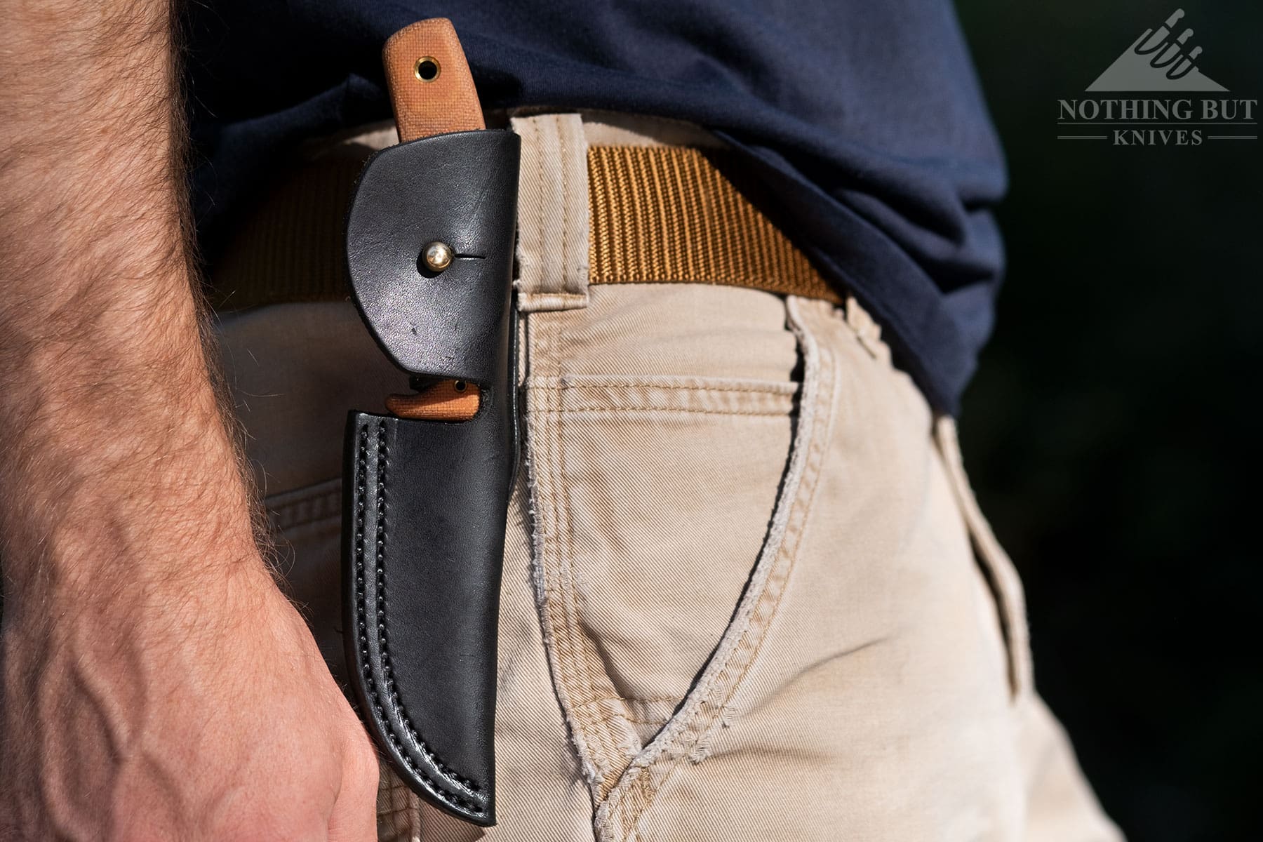 A close-up shot of the CRKT Soldotna inside its sheath on a person's belt.