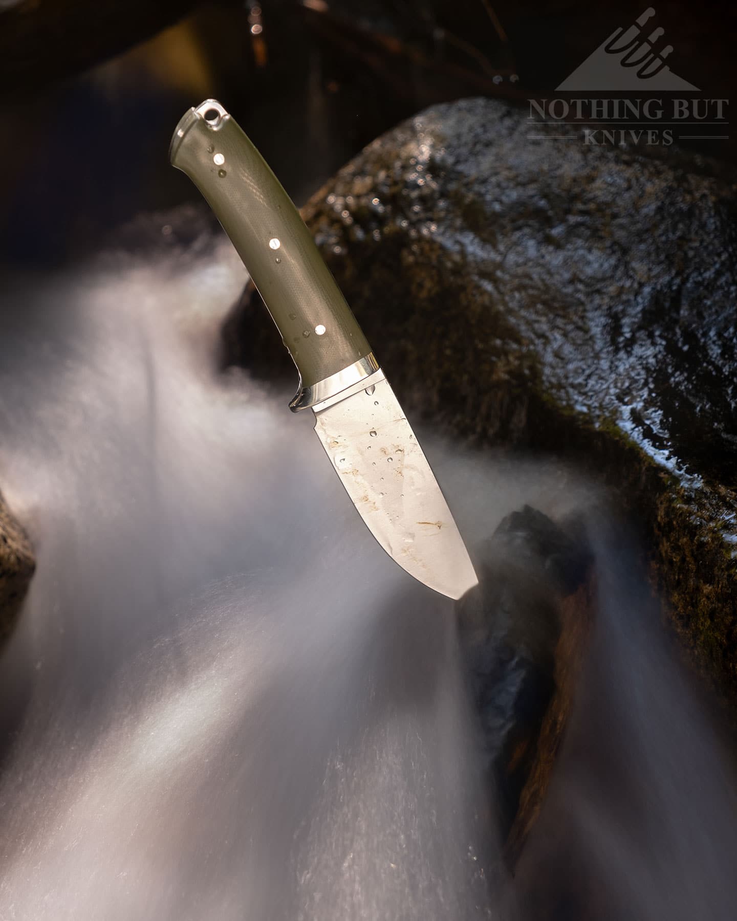 The Civivi Cloud Peak knife  with the blade stuck in a piece of driftwood in a creek.